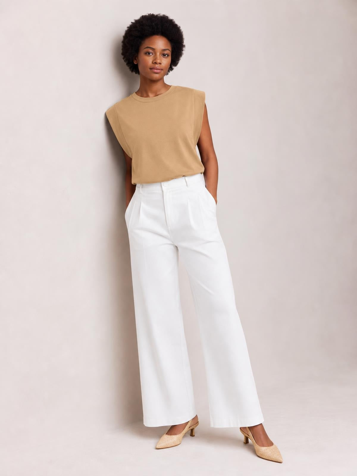 A model wears the tan Florira round neck cap sleeve T-shirt, featuring a relaxed, boxy silhouette, smooth opaque fabric, and subtle neckline trim.
