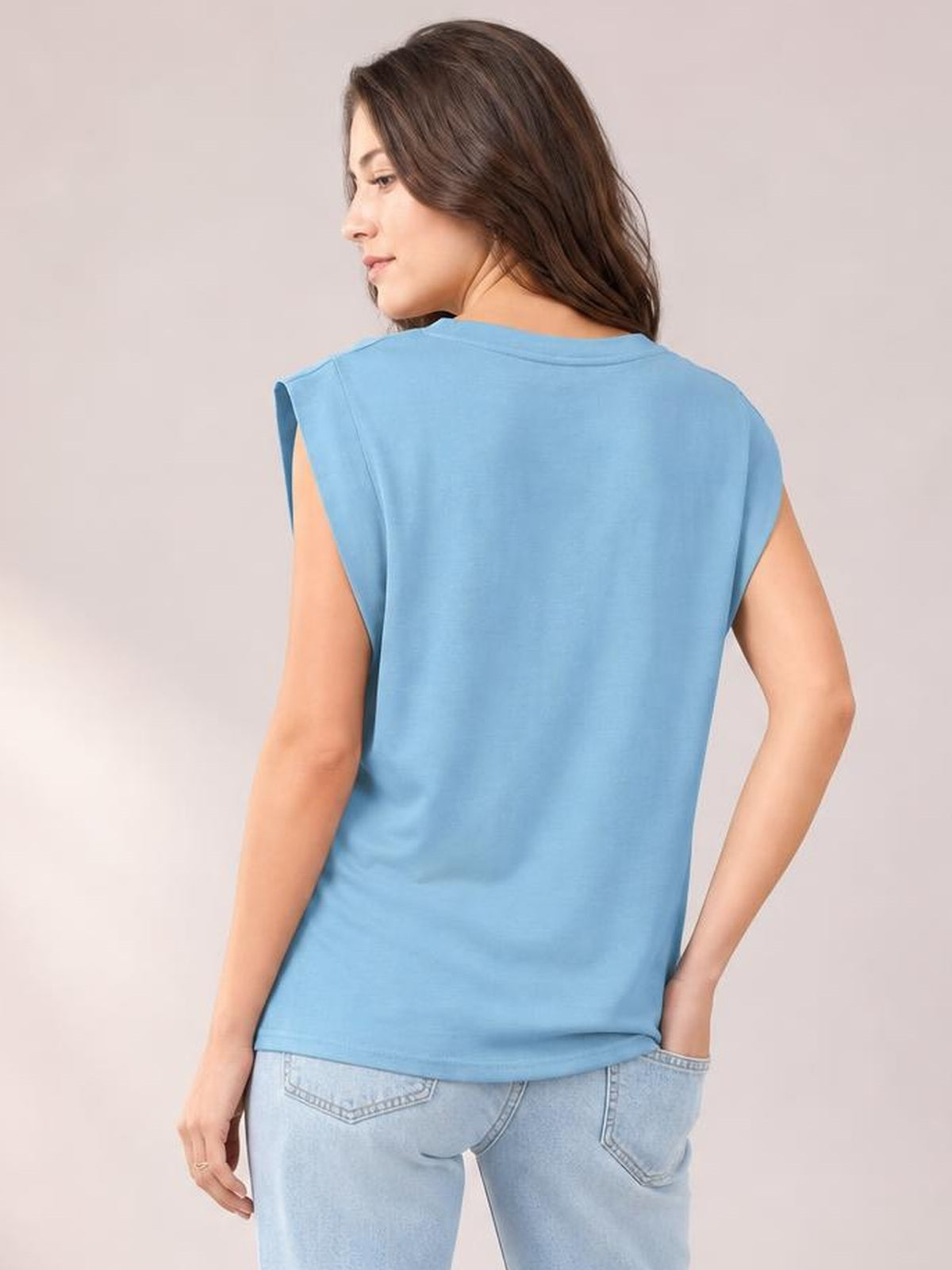 A model turns to show the sky-blue Florira round neck cap sleeve T-shirt, featuring an opaque fabric and relaxed straight silhouette.
