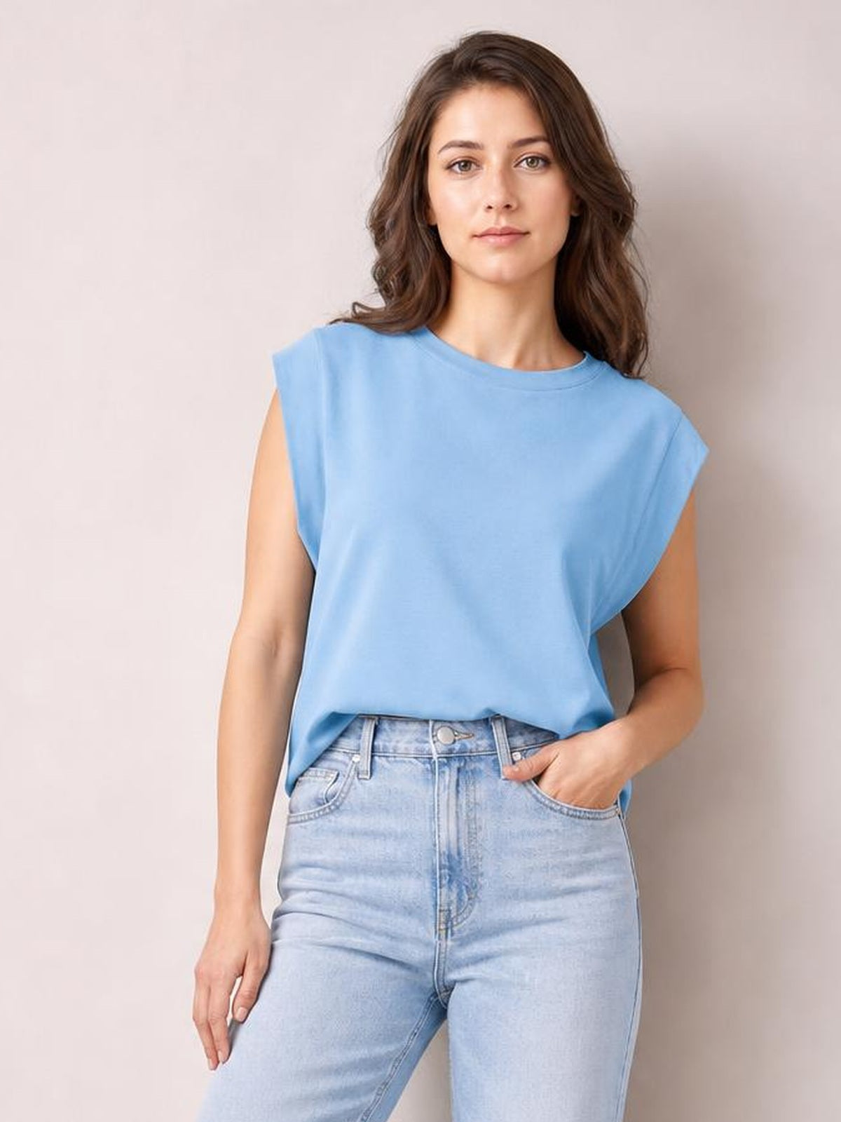 Model wears a light blue Florira round neck cap sleeve T-shirt with a relaxed silhouette, slightly stretchy opaque construction, and one hand in her jeans pocket.