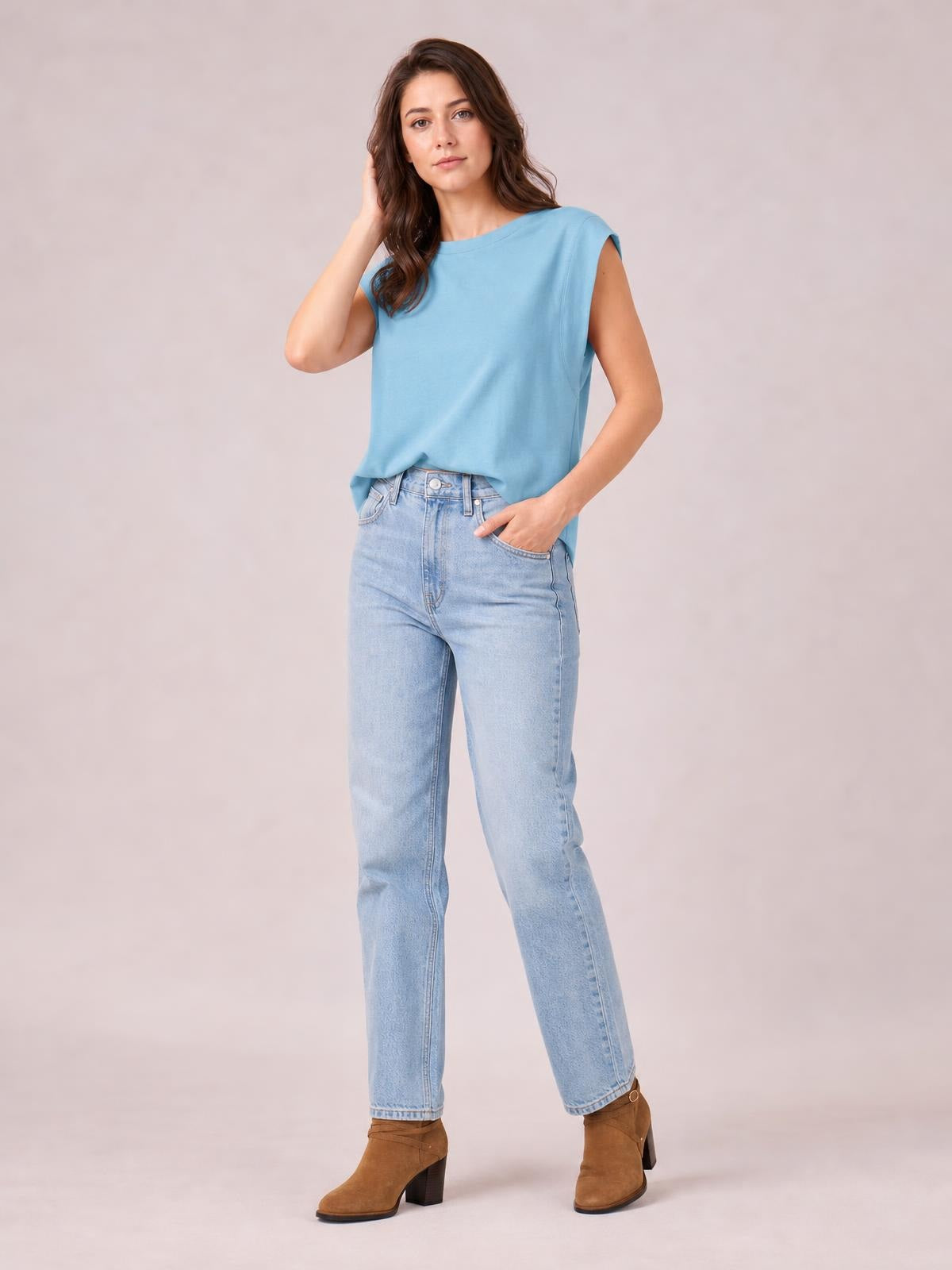 Model wears a blue Florira round neck cap sleeve T-shirt with a relaxed, slightly stretchy silhouette, posing with one hand in her jeans pocket.