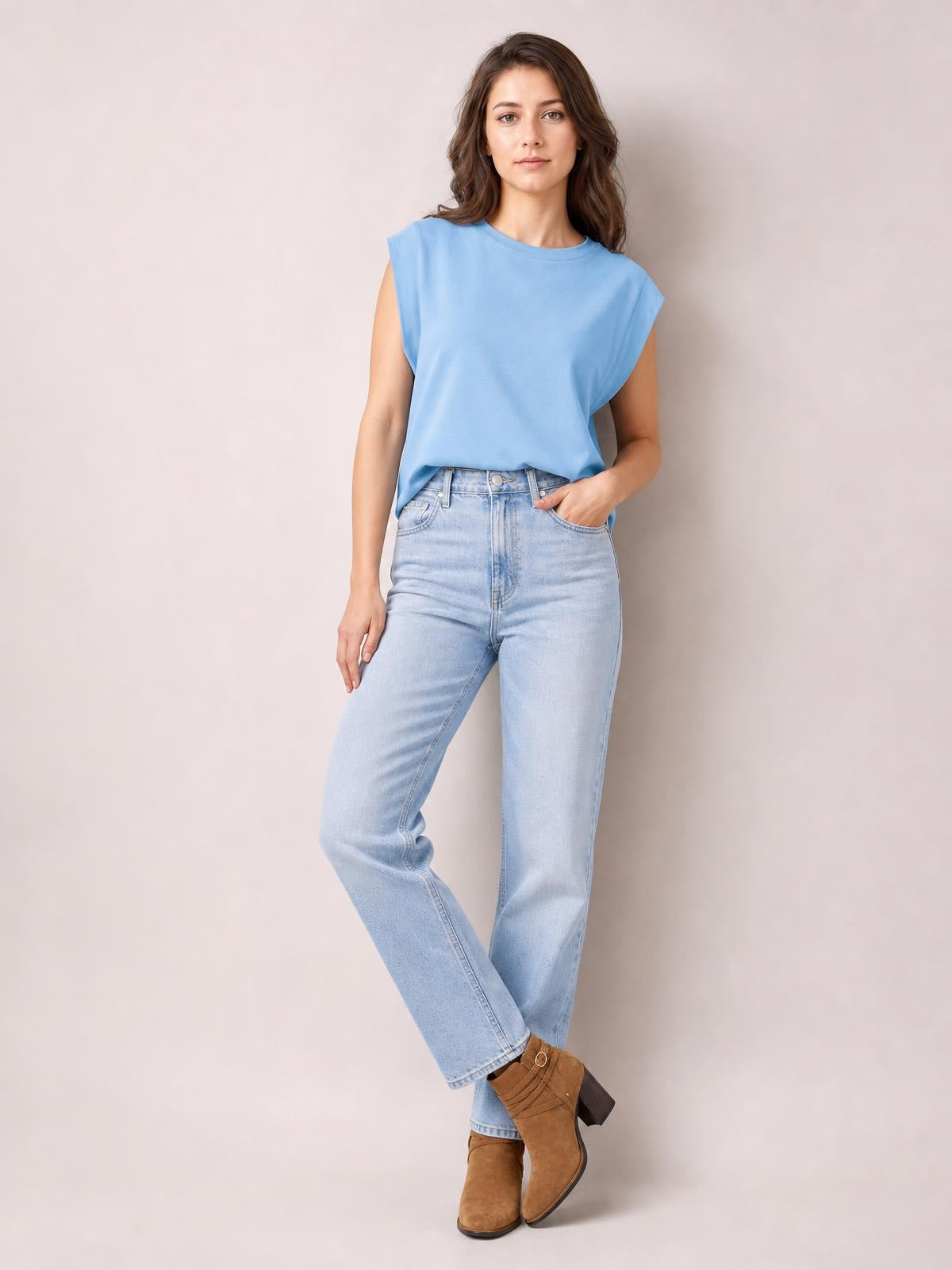 Model wearing a light blue Florira round neck cap sleeve T-shirt with a relaxed silhouette, tucked into jeans while posing with one hand in a pocket.