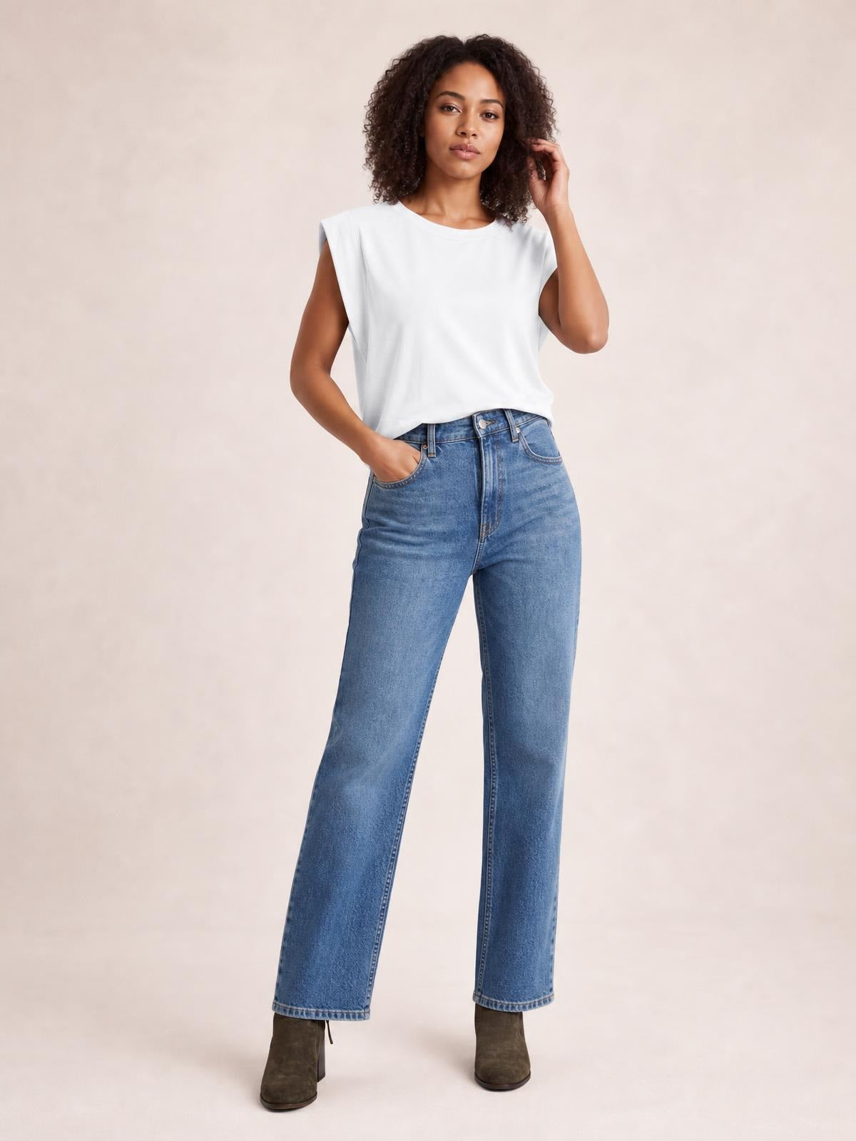 Model poses in a white Florira round neck cap sleeve T-shirt with a relaxed straight silhouette, paired with blue jeans.
