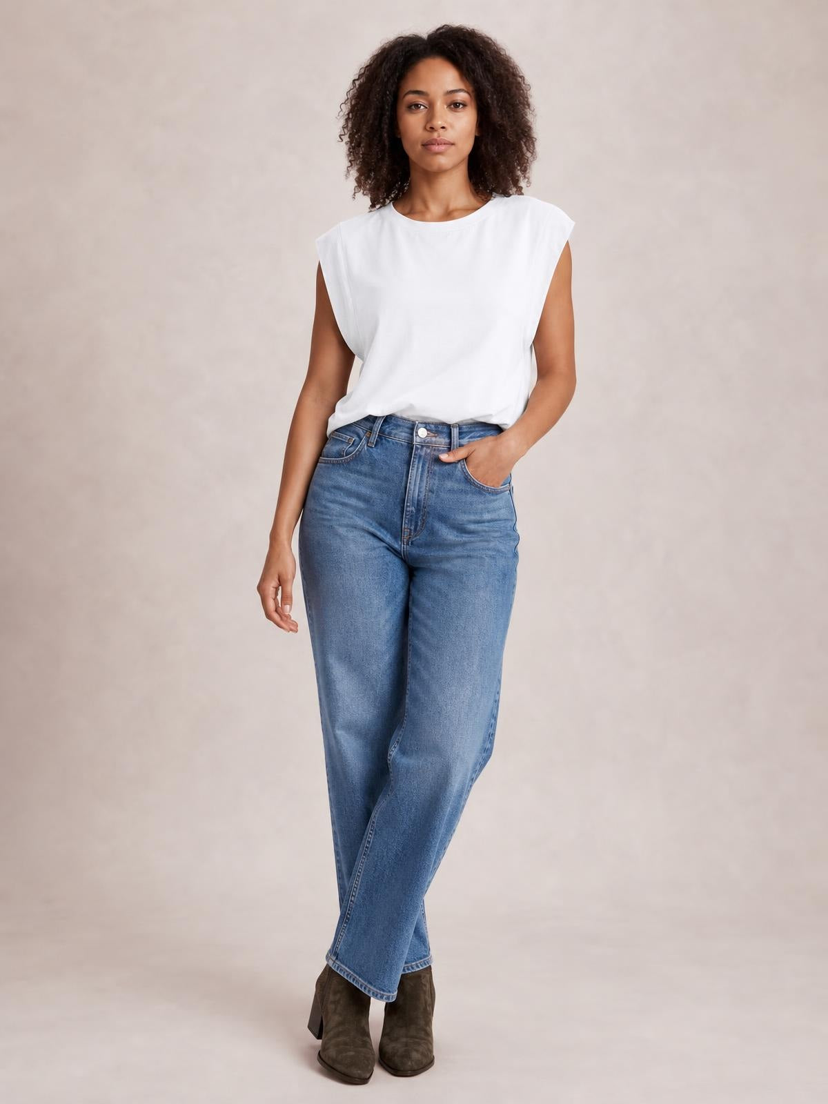 Model wears a white Florira round neck cap sleeve T-shirt with a relaxed silhouette, standing with one hand in her jeans pocket.
