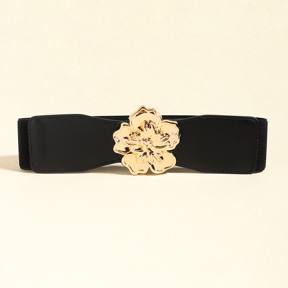 Black wide elastic belt with a gently contoured silhouette, stitched edges, and a polished gold-tone alloy floral buckle at the center.