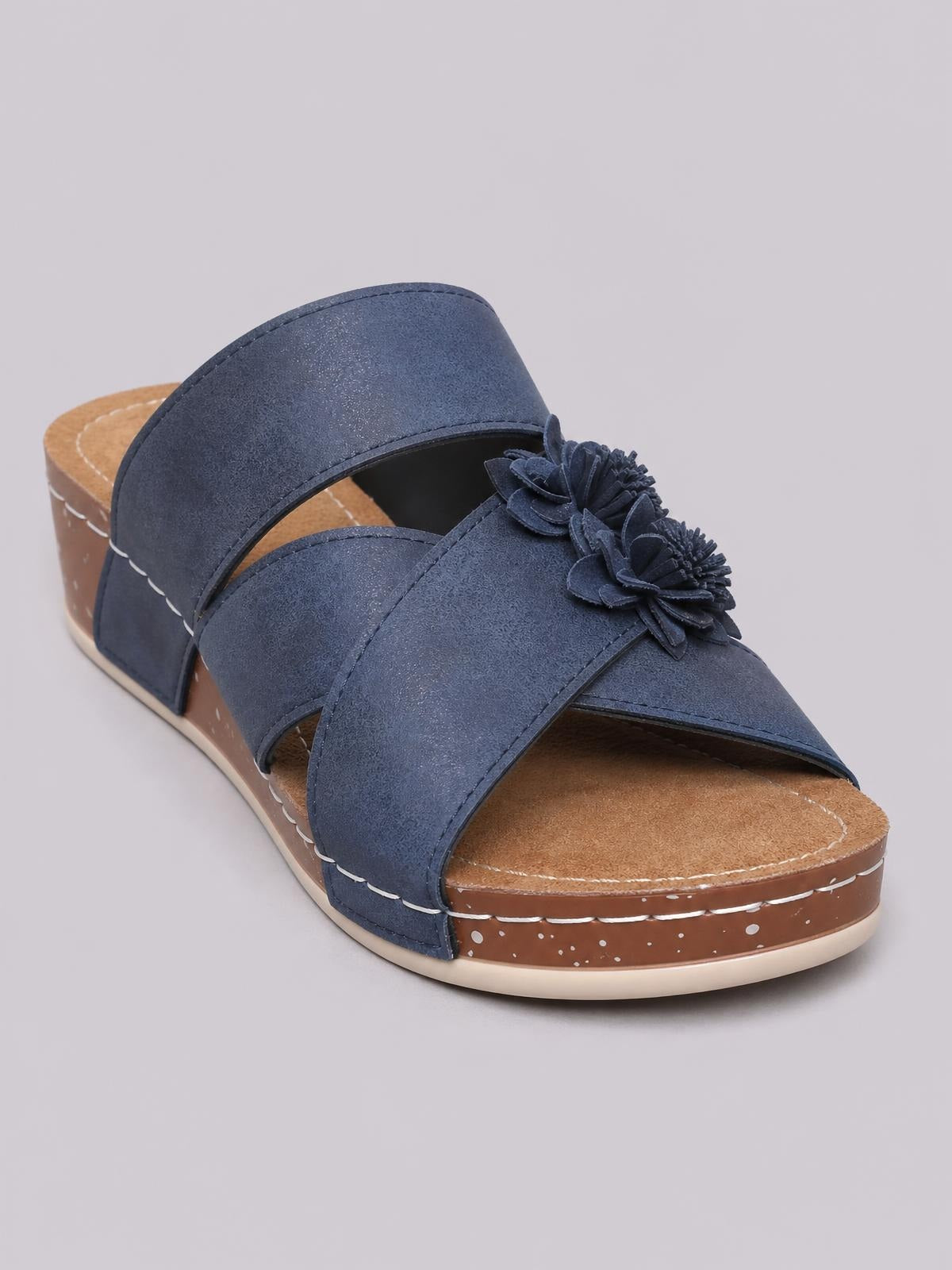 Navy blue flower crisscross wedge sandals feature layered floral embellishments, open toes, broad crossed straps, and a mid-height wedge sole with contrast stitching.