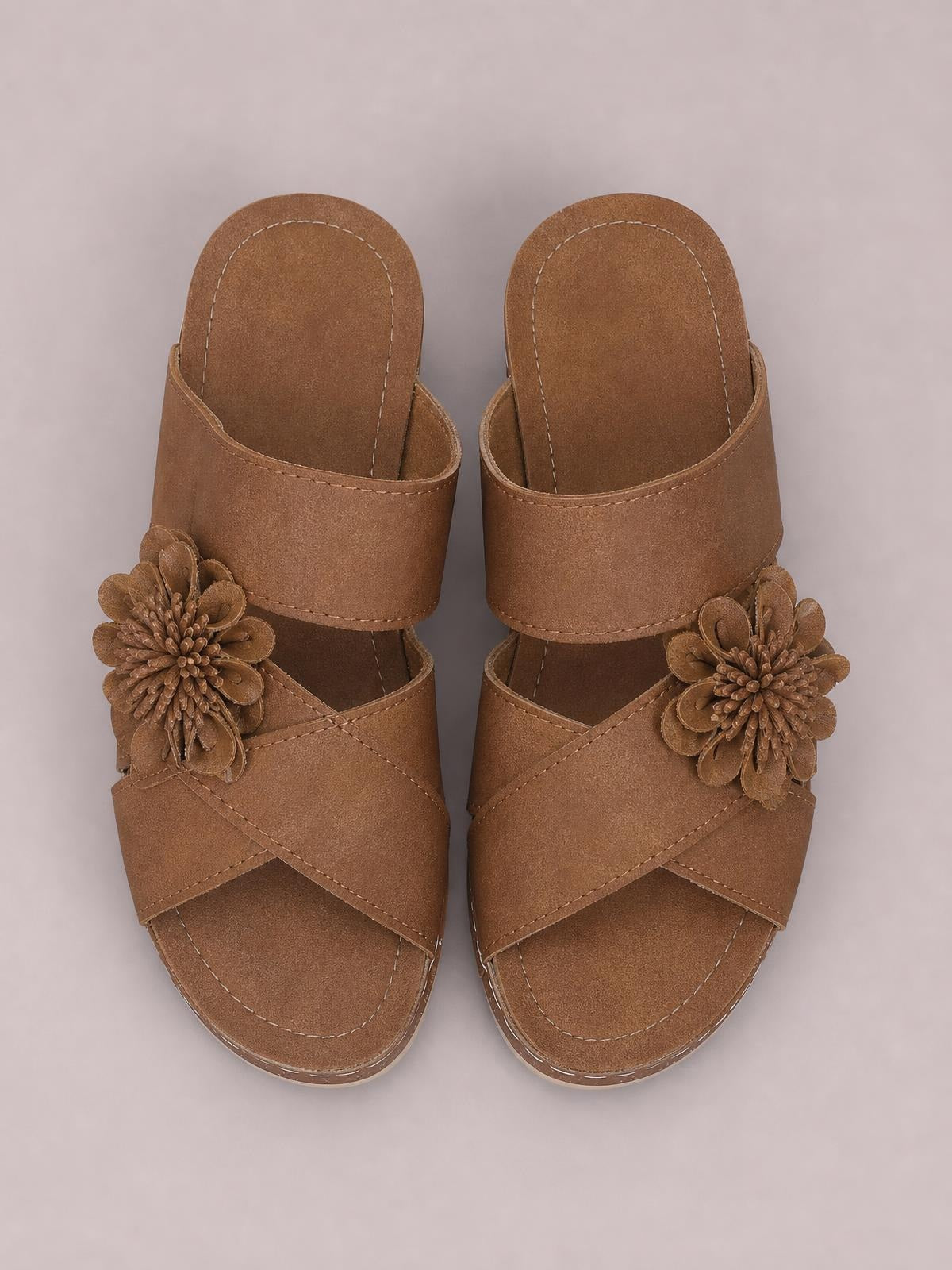 Brown flower crisscross wedge sandals with layered floral accents, wide crossover straps, open toes, stitched footbeds, and mid-height wedge heels.
