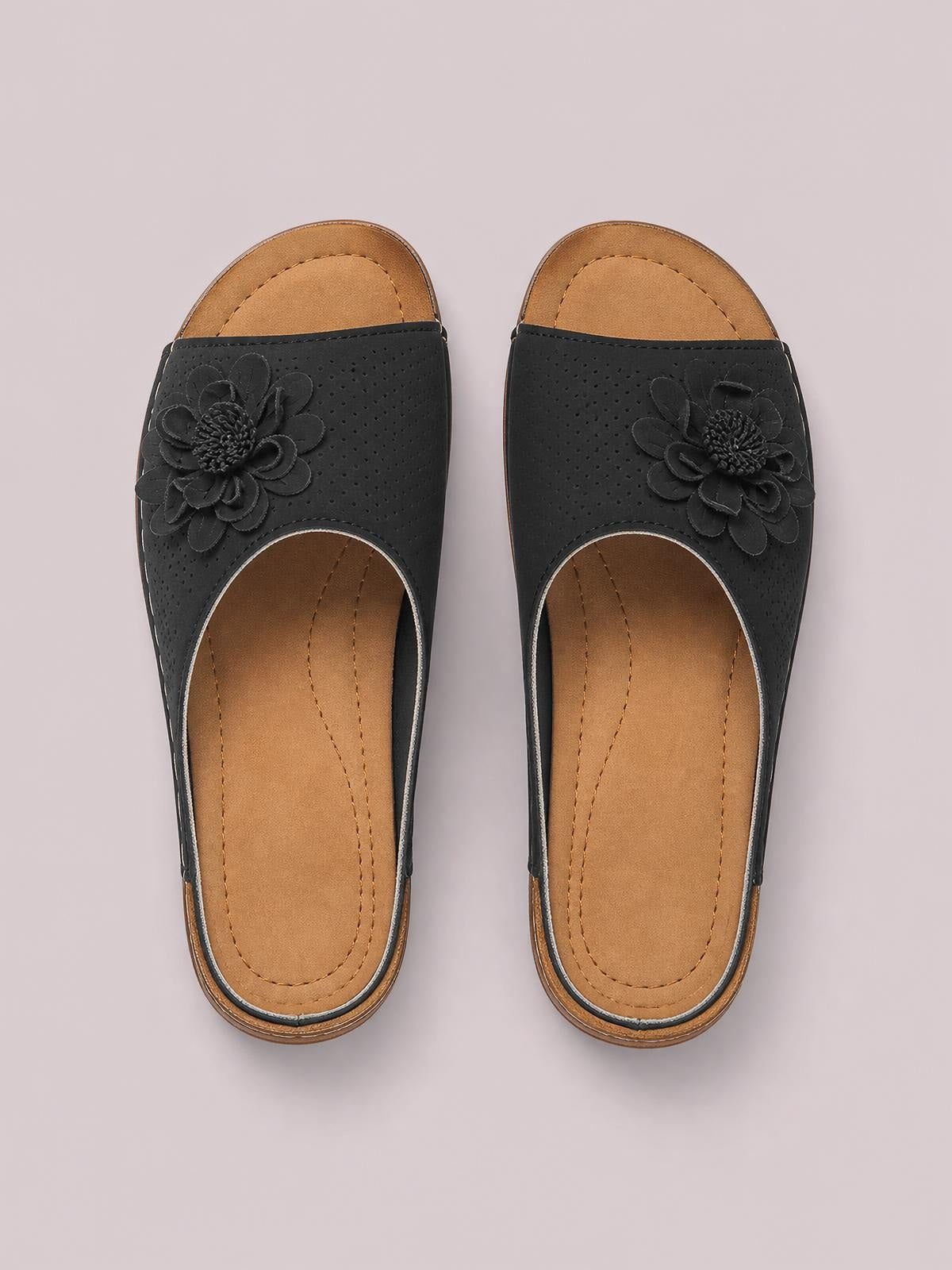 Black flower peep toe wedge sandals with perforated uppers, tan cushioned footbeds, stitched construction, and low platform wedge soles.