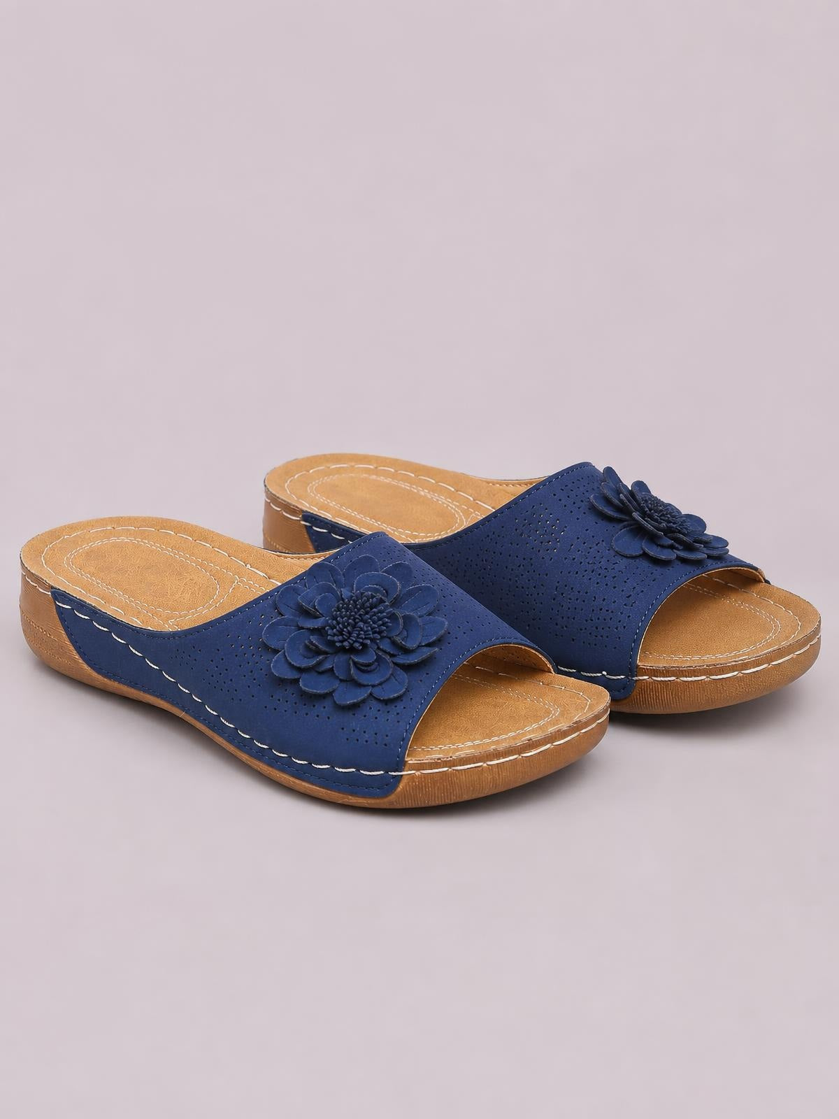 Blue flower peep-toe wedge sandals feature perforated uppers, layered floral appliqués, tan footbeds, low wedge heels, and contrast stitching.