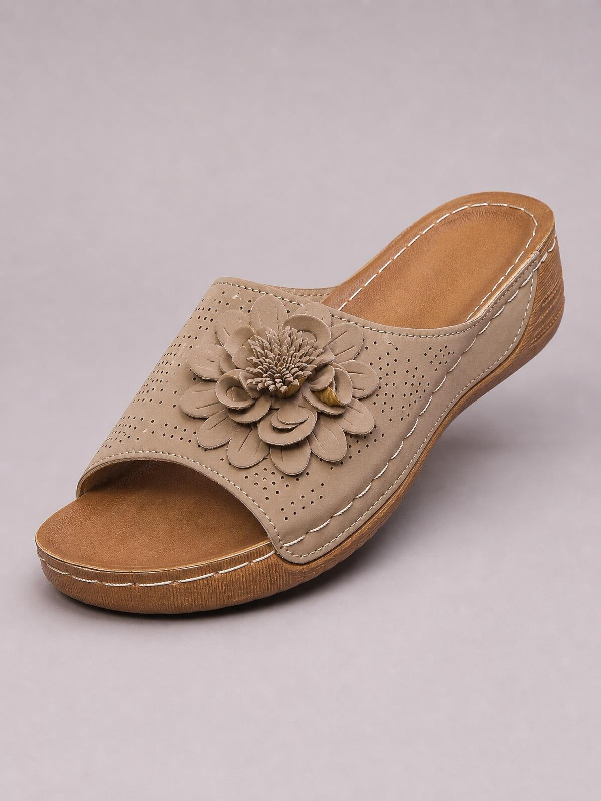 Beige flower peep toe wedge sandal with a layered floral applique, perforated upper, open-back mule silhouette, and low stitched wedge sole.