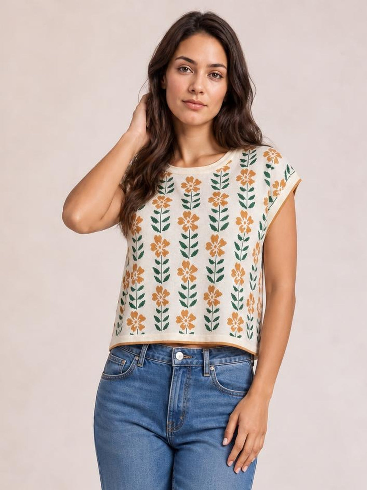 Model poses in a cream knit top with a round neck, short sleeves, orange flower and green leaf print, contrast trim, and a relaxed straight silhouette.