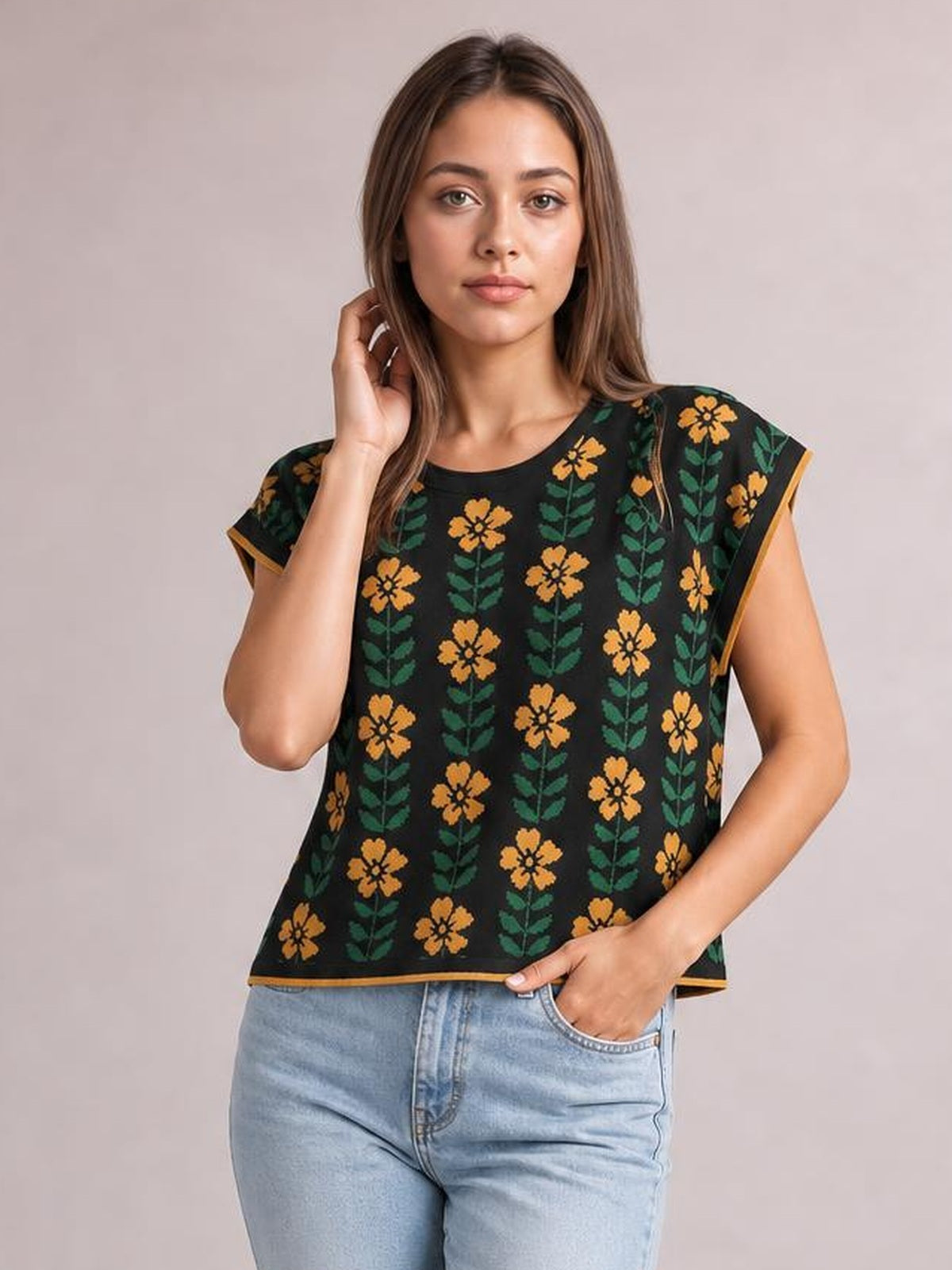 Model wearing a black flower-print knit top with a round neck, short sleeves, relaxed straight silhouette, and contrasting orange-trimmed edges.