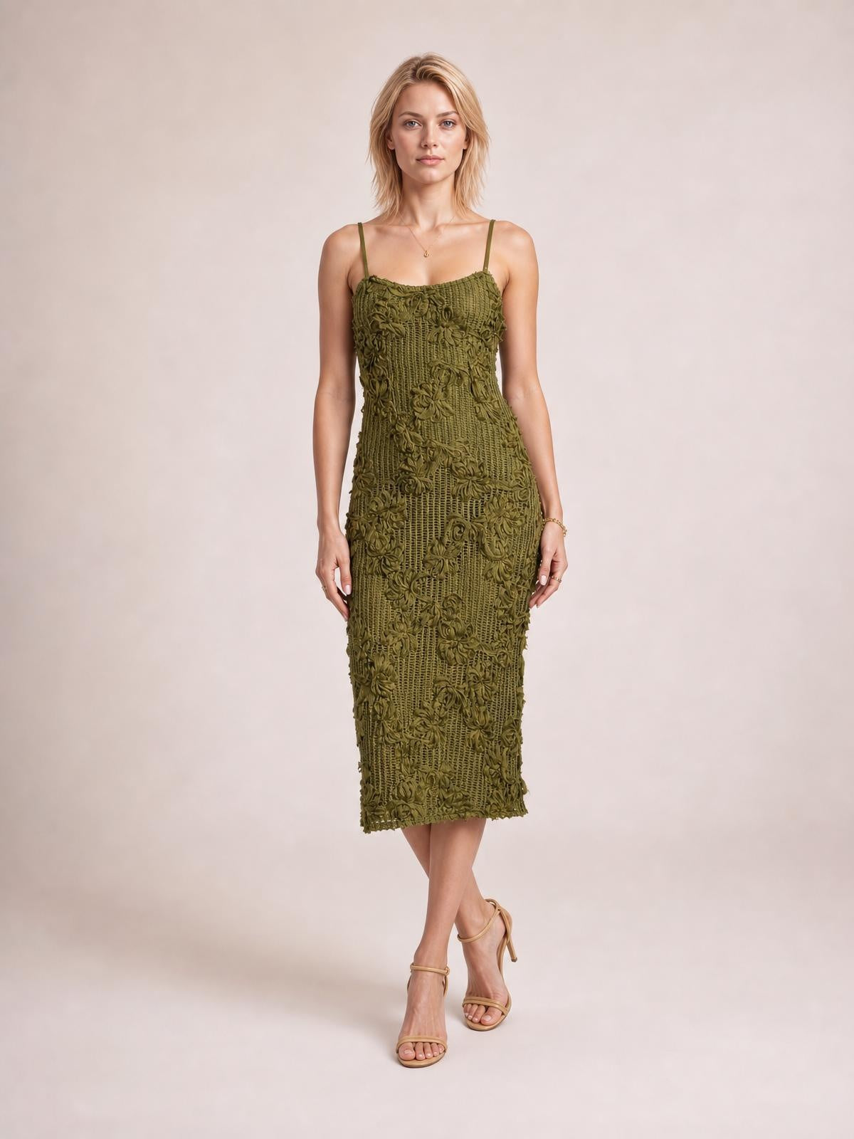 Model poses in an olive midi cami dress with delicate spaghetti straps, a figure-skimming silhouette, and dimensional floral cable-knit texture.