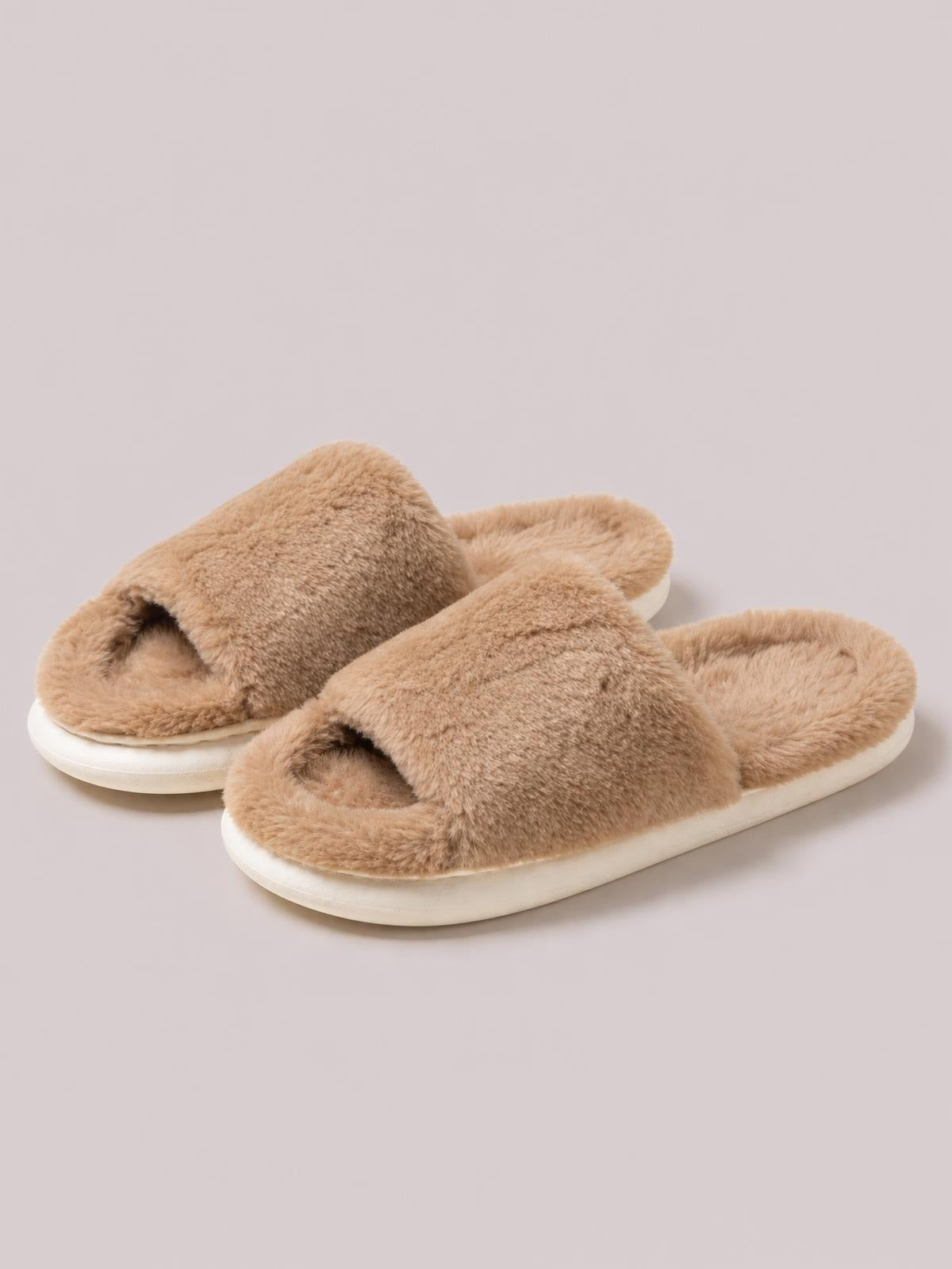 Fluffy tan open-toe comfort slippers feature wide crossed plush straps and cushioned flat soles with a rounded silhouette.