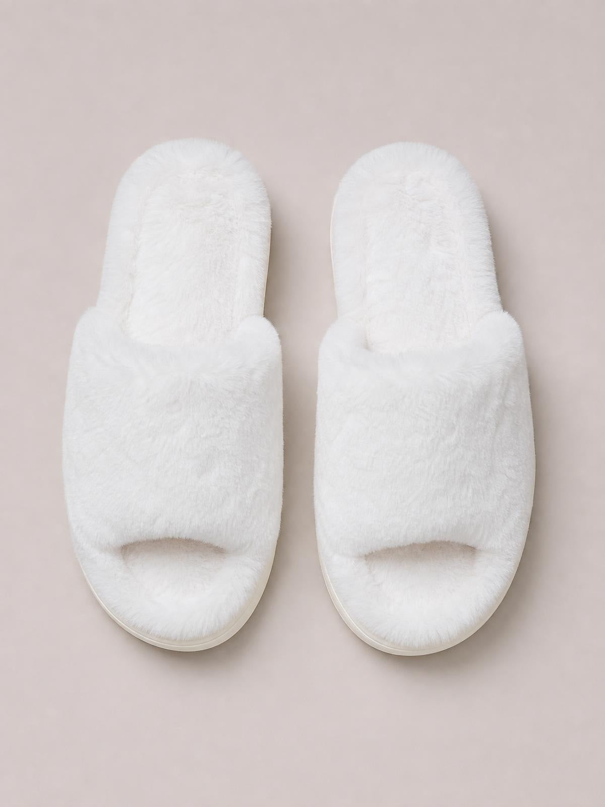 White fluffy open-toe comfort slippers with plush wide straps, cushioned footbeds, rounded toes, and flat rubber or PVC soles.