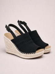 Black peep-toe high heel sandals with textured woven uppers, adjustable ankle straps, and tall espadrille wedge heels in a platform silhouette.