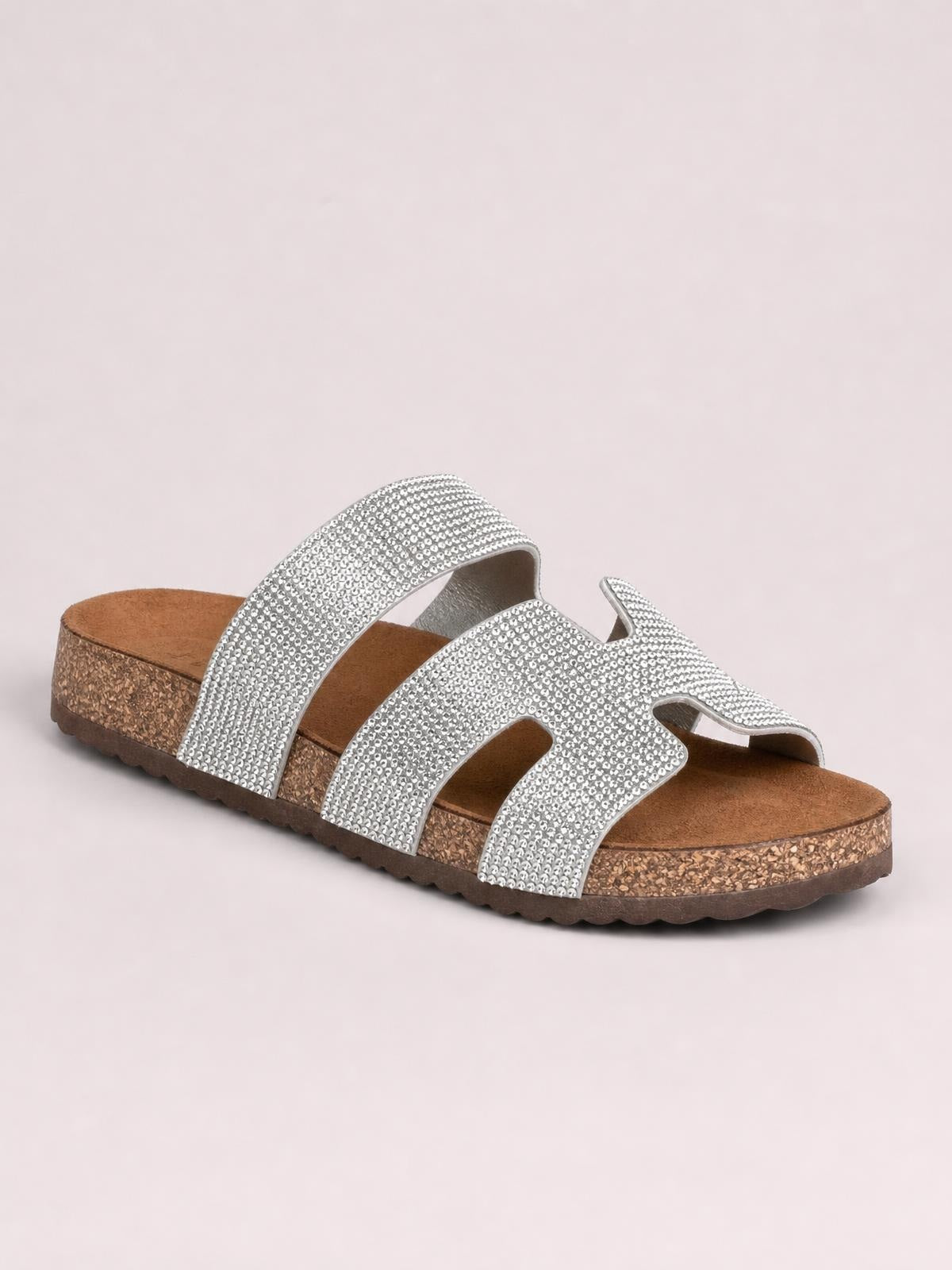 Silver rhinestone open toe sandals feature multiple wide embellished straps, a contoured brown footbed, cork-effect platform sole, and flat construction.