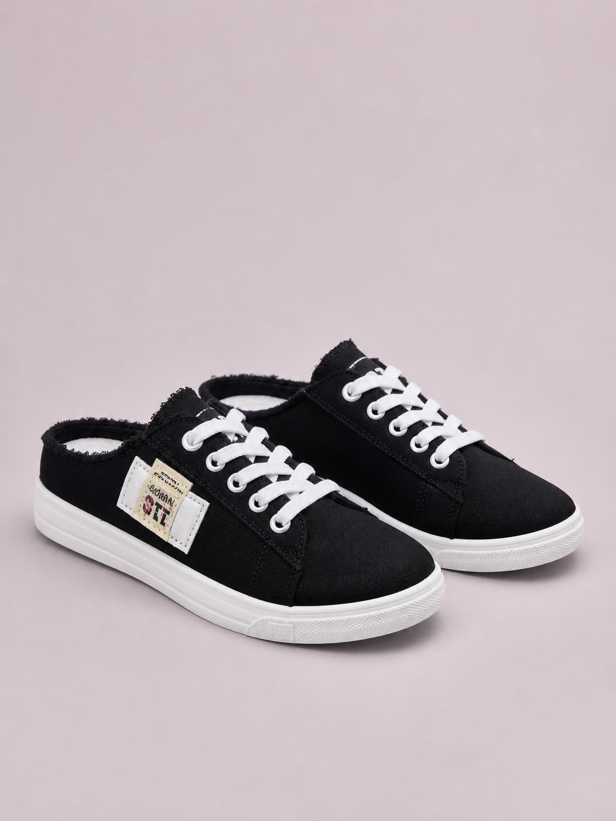 Black canvas lace-up sneakers feature frayed edges, white laces, contrast stitching, and low-profile white rubber soles for a casual flat silhouette.