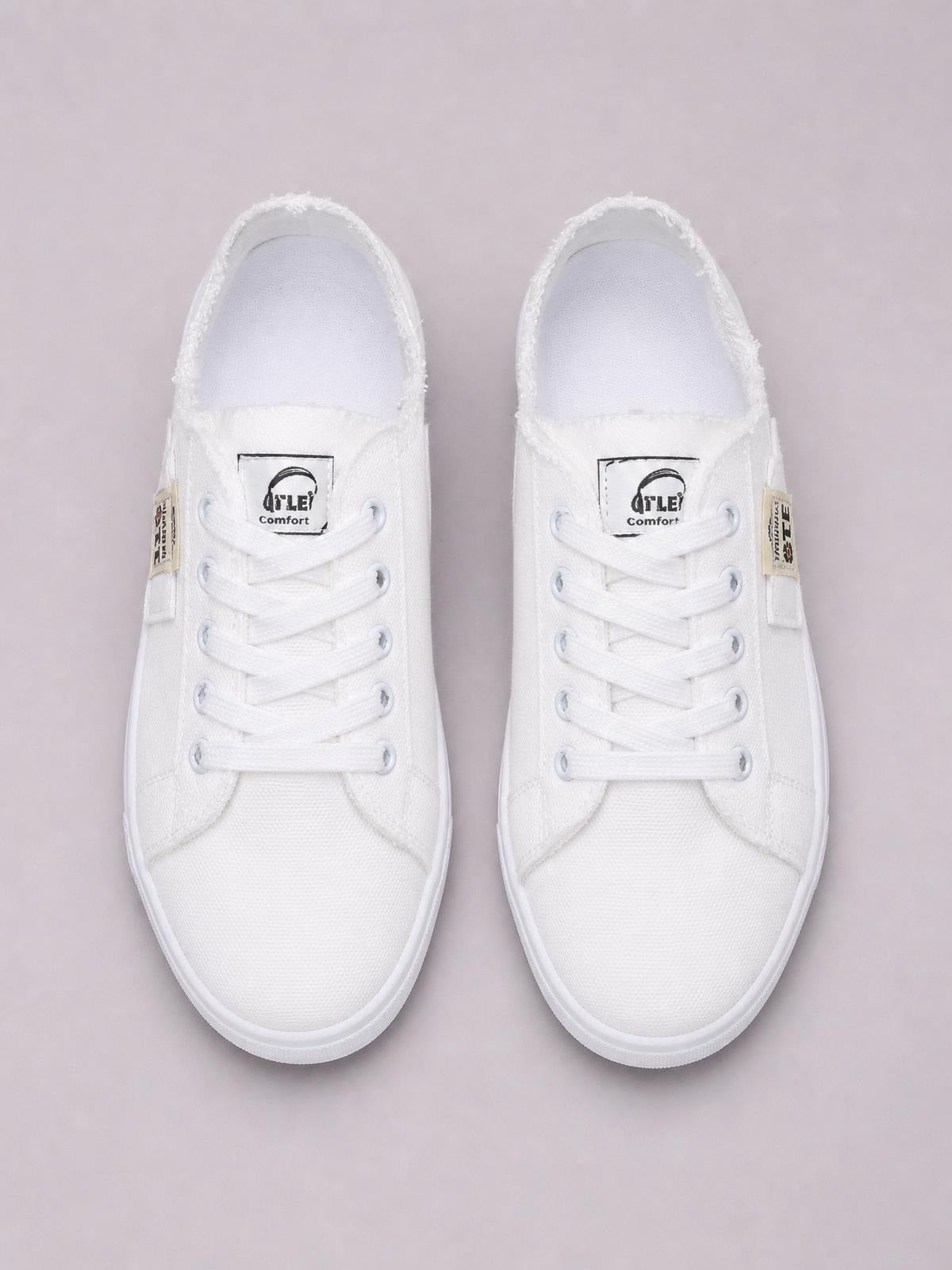 A pair of white canvas lace-up sneakers with frayed hems, rounded toes, tonal eyelets, and flat rubber soles.