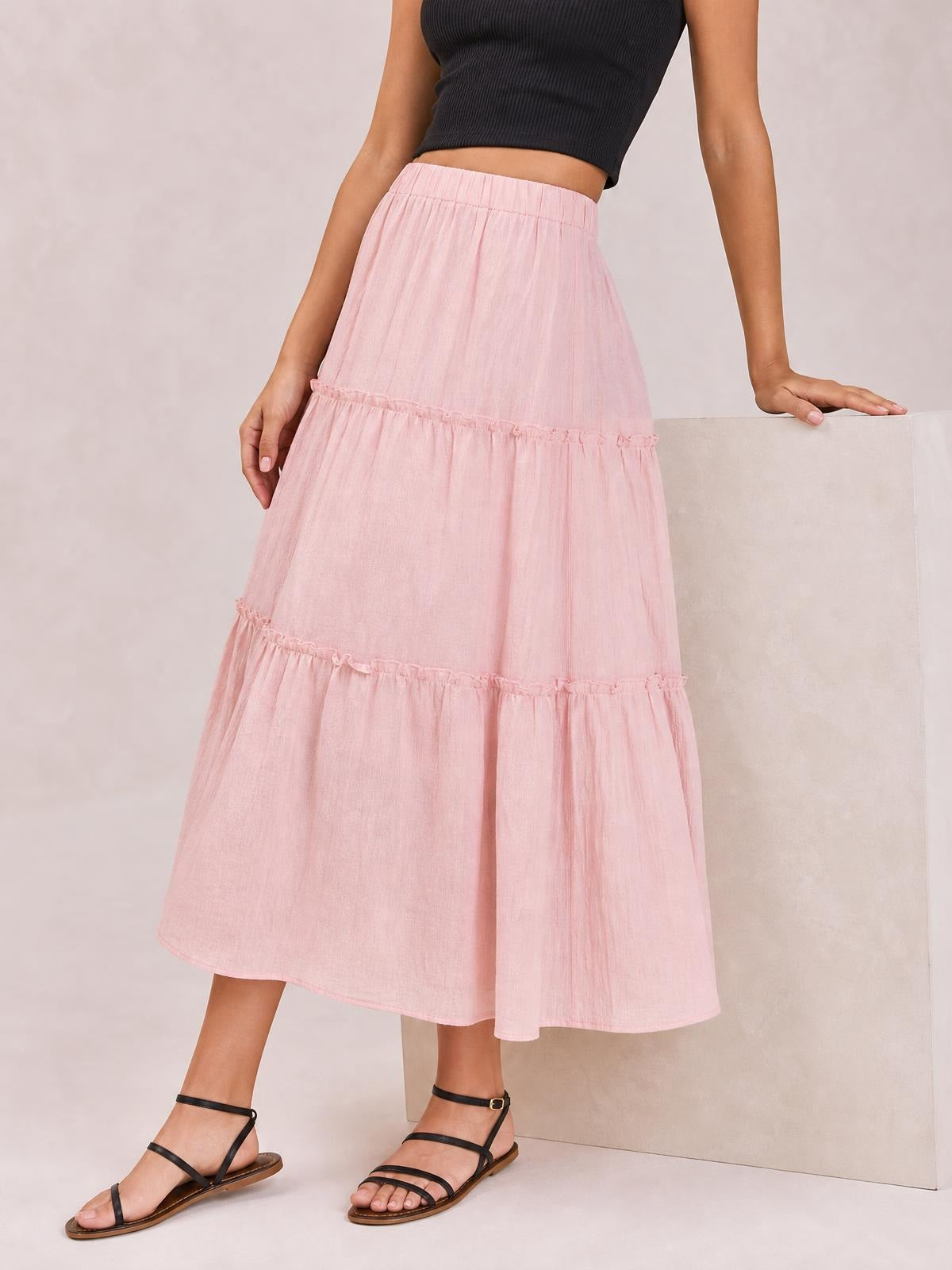 Model wearing a pink Frill Elastic Waist Skirt with a gathered waistband, tiered ruffle details, lined opaque construction, and a flowing midi silhouette.