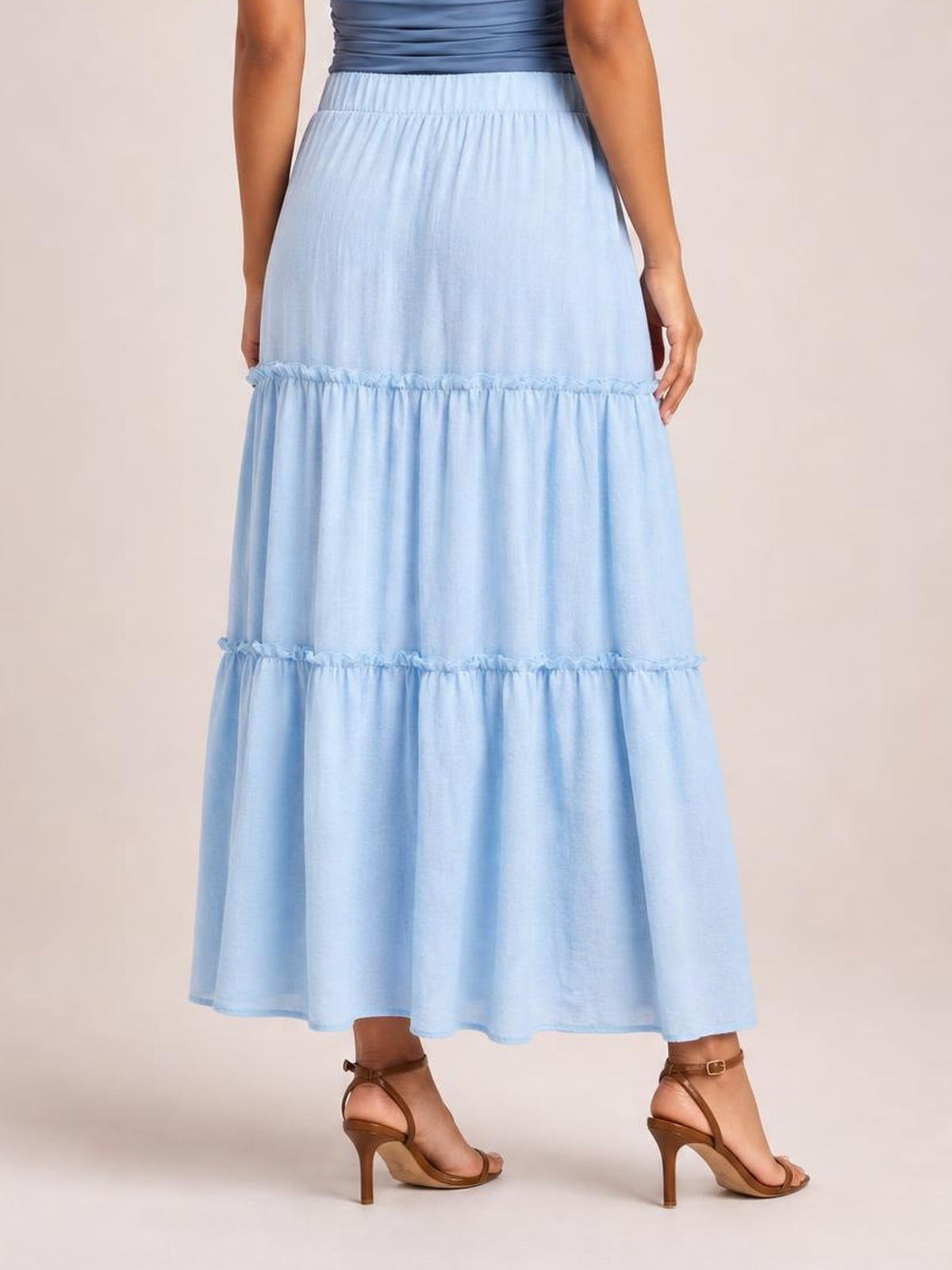 Model stands in a side-facing pose wearing a light blue Frill Elastic Waist Skirt with a flowing long silhouette, gathered tiers, and ruffled seams.