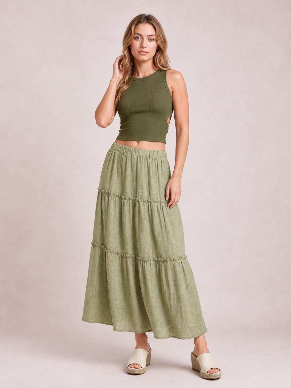 Model poses in a sage green Frill Elastic Waist Skirt with a comfortable gathered waistband, tiered maxi silhouette, and delicate frill trim.