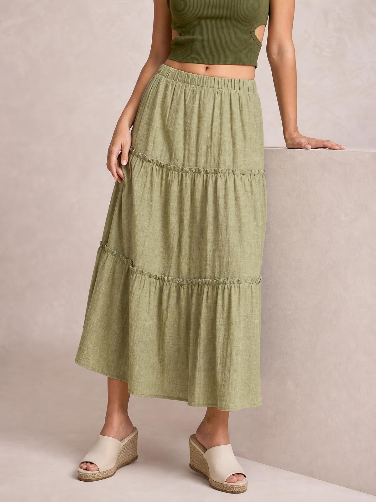 Model wears an olive green Frill Elastic Waist Skirt with a gathered waistband, tiered ruffle details, and a flowing midi silhouette.
