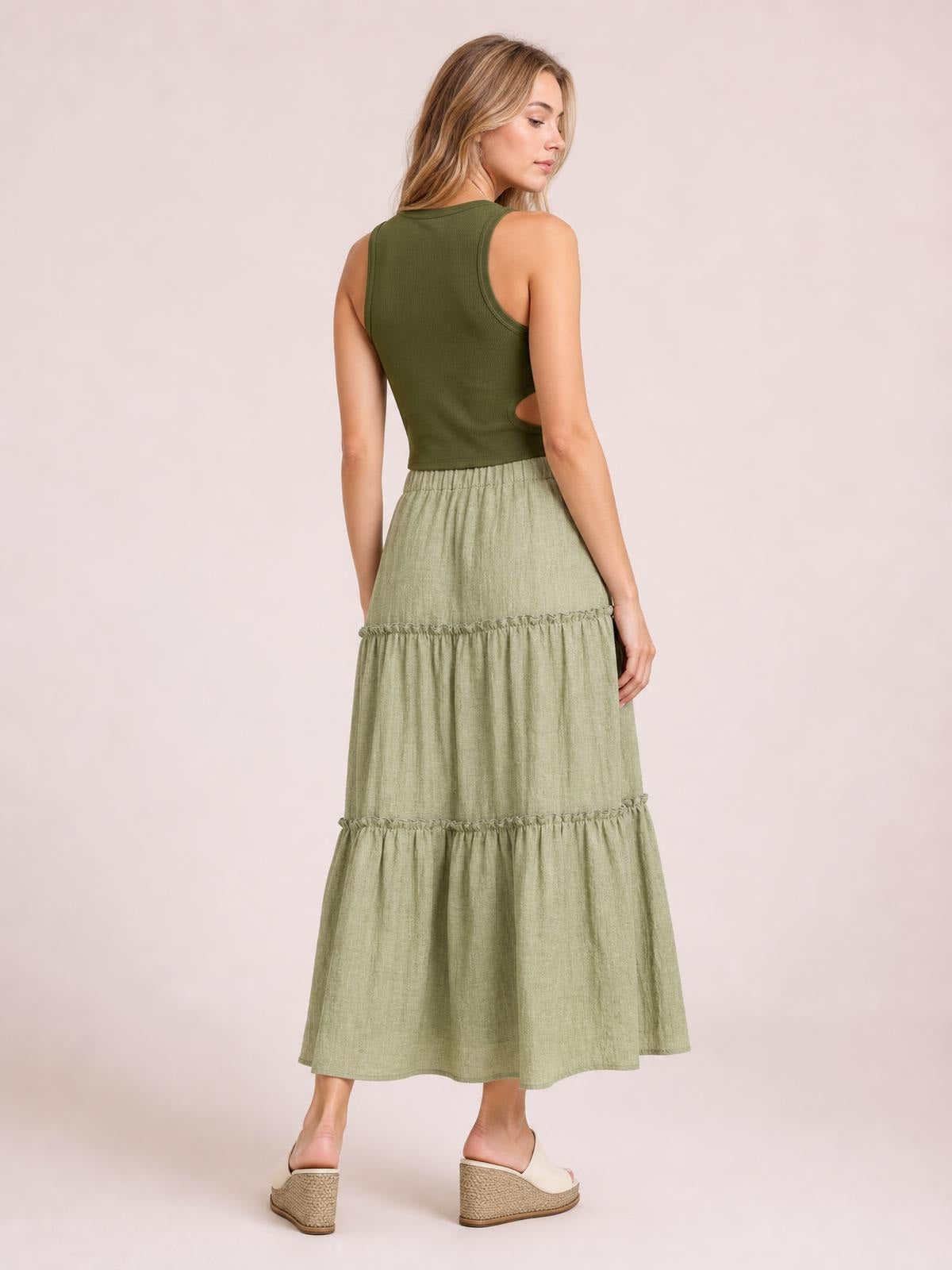 Model shown from behind wearing a sage green Frill Elastic Waist Skirt with a tiered maxi silhouette, gathered waistband, and ruffled seams.