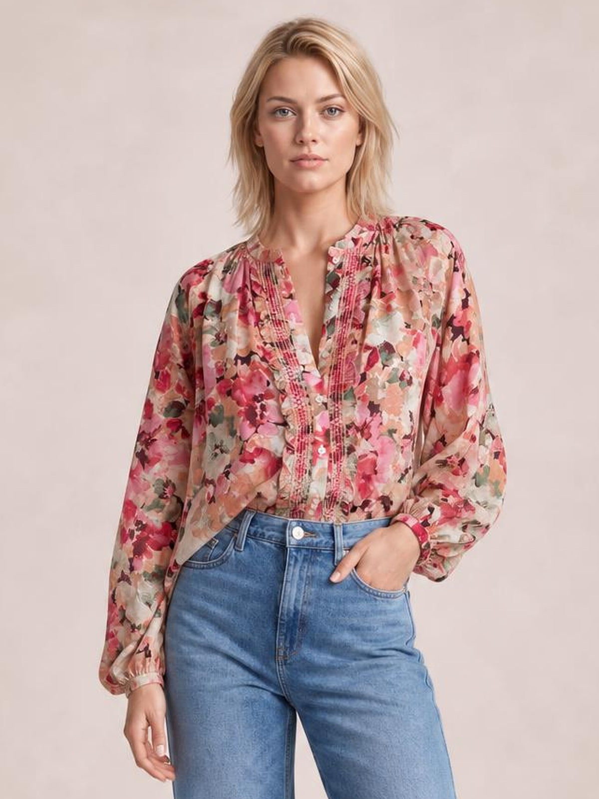 A model stands in a pink floral button-down shirt with long sleeves, frill-trimmed front, gathered neckline, and a relaxed silhouette, one hand in her jeans pocket.