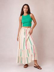 Model poses in a flowy cream Frill Printed Maxi Skirt with colorful vertical chevron print, tied waist, and tiered frill construction.