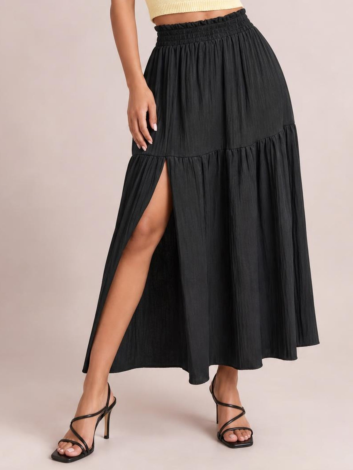 Model wears a black Frill Slit Skirt with a gathered waistband, tiered construction, flowing midi silhouette, and high front slit.