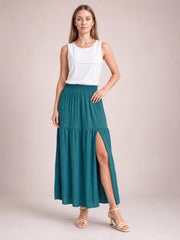 Model poses in a teal Frill Slit Skirt with an elastic waistband, flowing maxi silhouette, gathered lower tier, and high side slit.