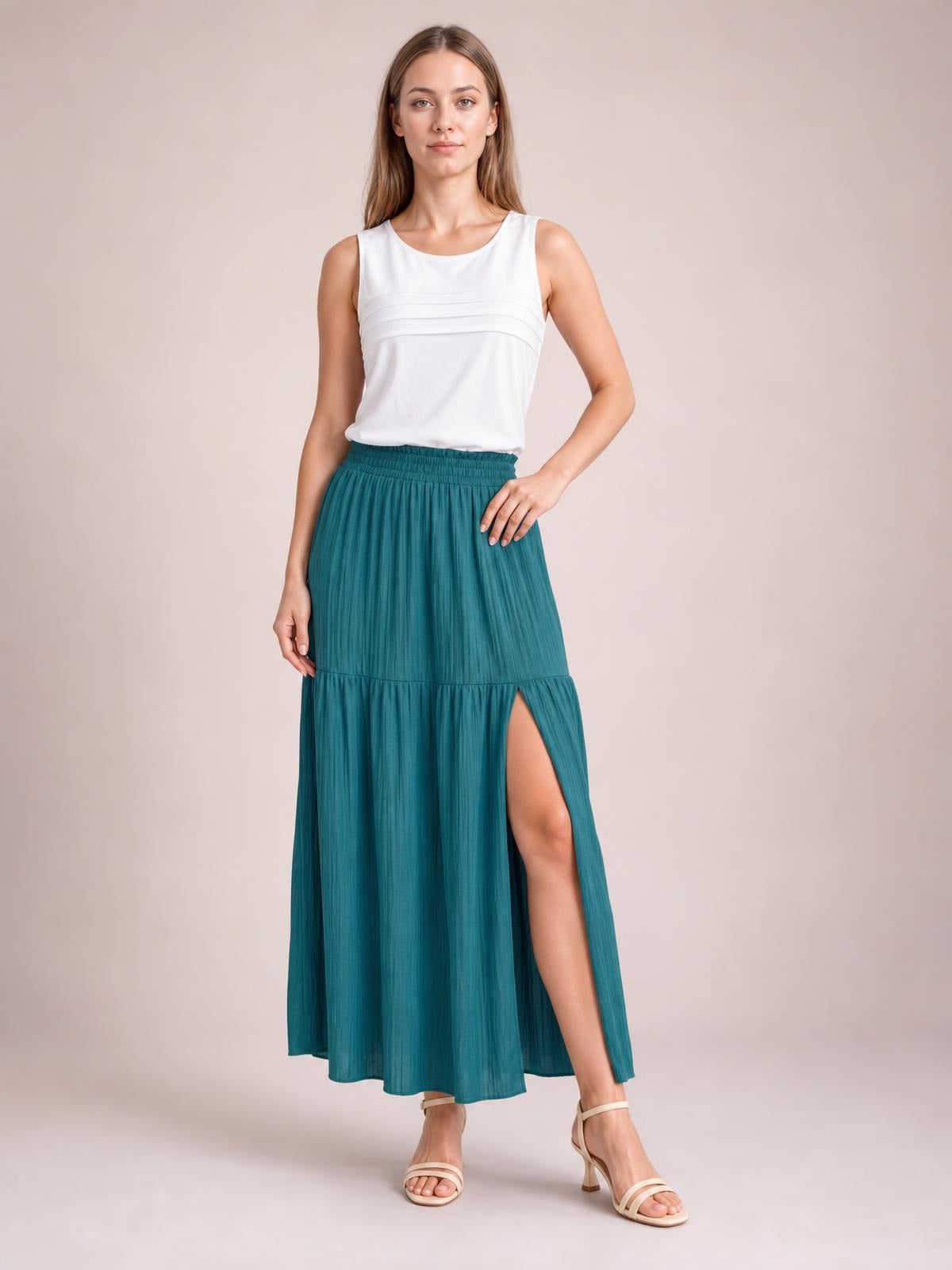 Model poses in a teal Frill Slit Skirt with an elastic waistband, flowing maxi silhouette, gathered lower tier, and high side slit.