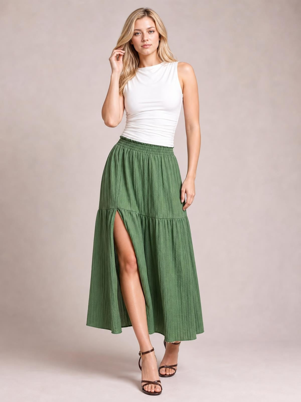 Model wearing a lightweight green Frill Slit Skirt with an elastic waist, flowing maxi silhouette, tiered construction, and a high front slit.