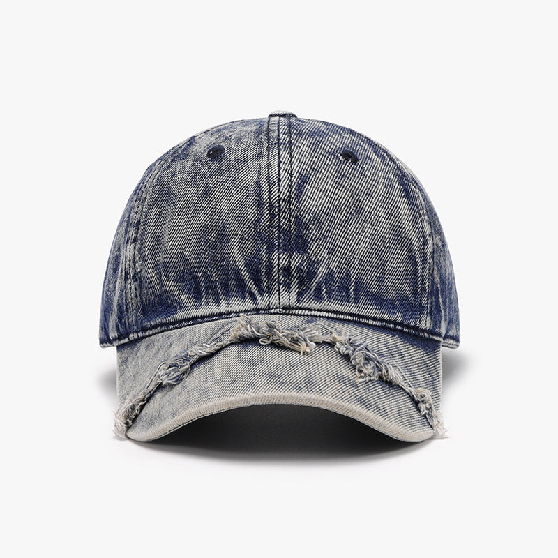 A distressed blue cotton baseball cap features a classic six-panel crown, curved brim, and distinctive fringe detailing along the front edge.