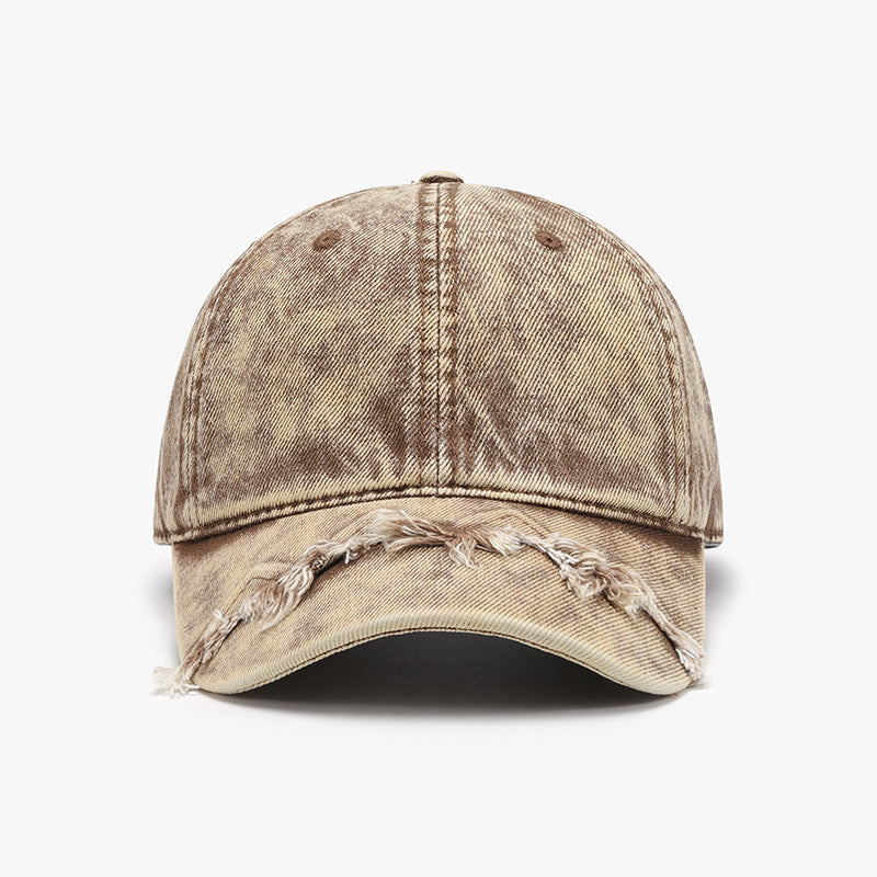 Distressed beige cotton baseball cap with a classic six-panel crown, curved brim, softly worn finish, and fringe detailing along the front edge.
