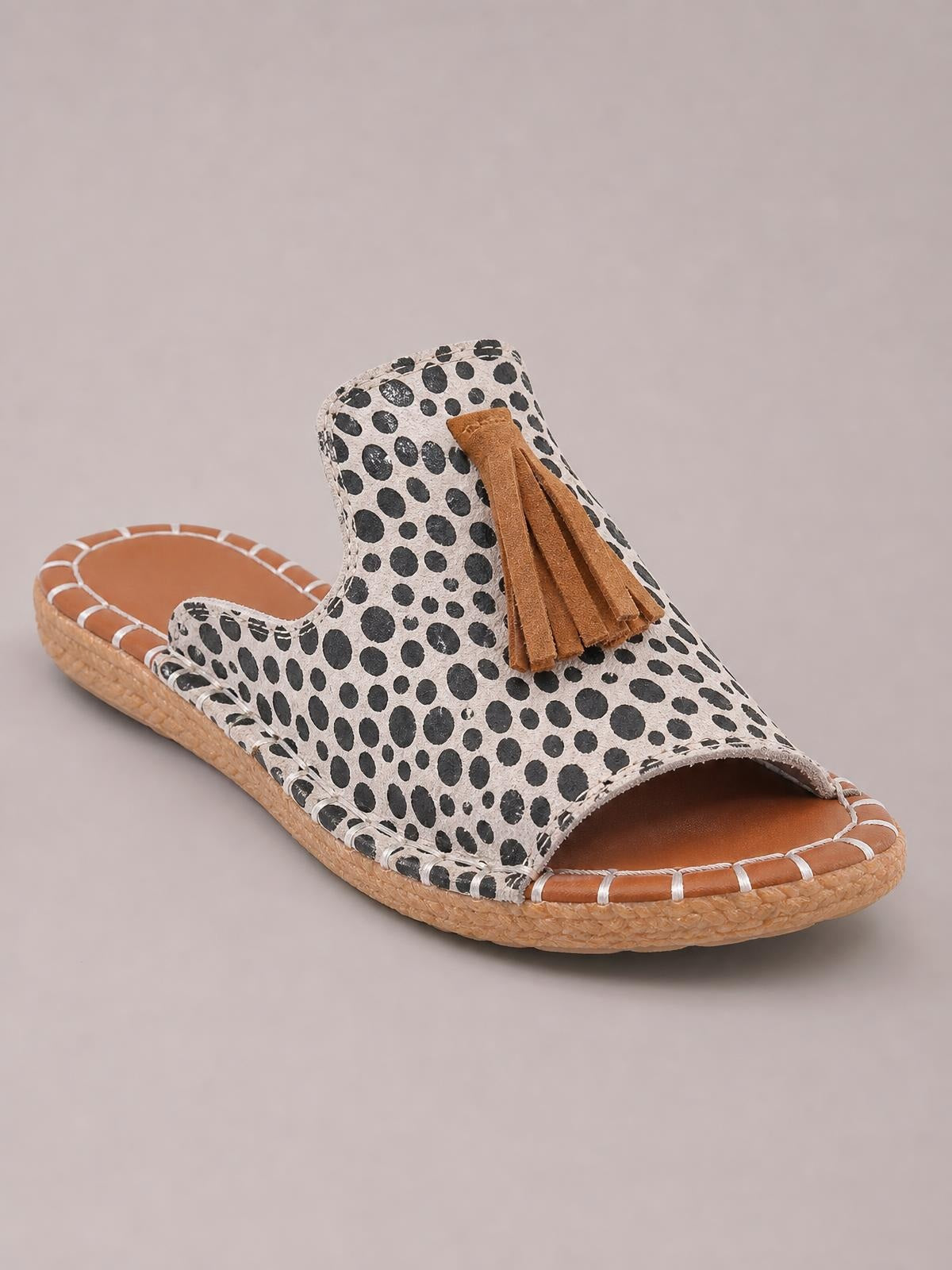 Leopard-print open-toe flat sandal with a tan textured sole, stitched trim, and long brown fringe detail on the upper.