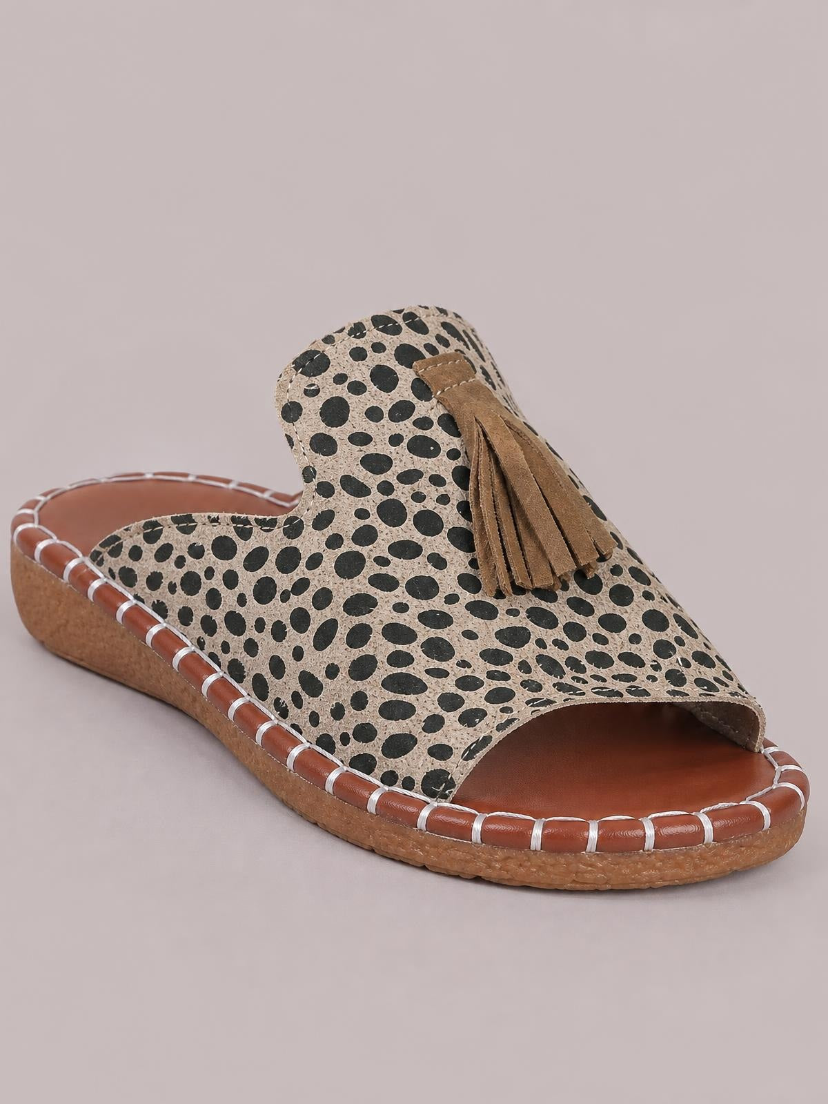 Leopard-print open-toe flat sandals feature a slip-on mule silhouette, tan footbed and sole, contrast stitching, and layered brown fringe across the upper.