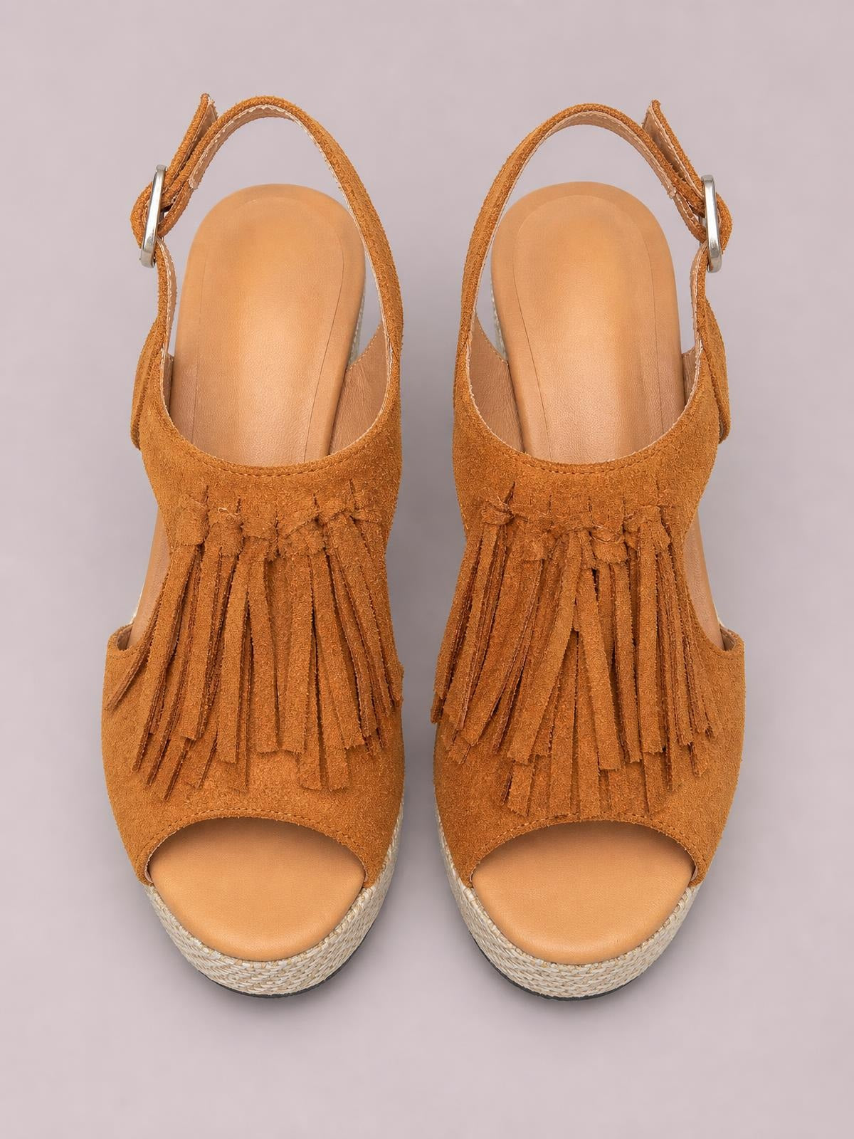 Tan suede fringe peep toe wedge sandals with layered tassels, ankle buckle straps, open sides, and textured woven mid-height wedge soles.