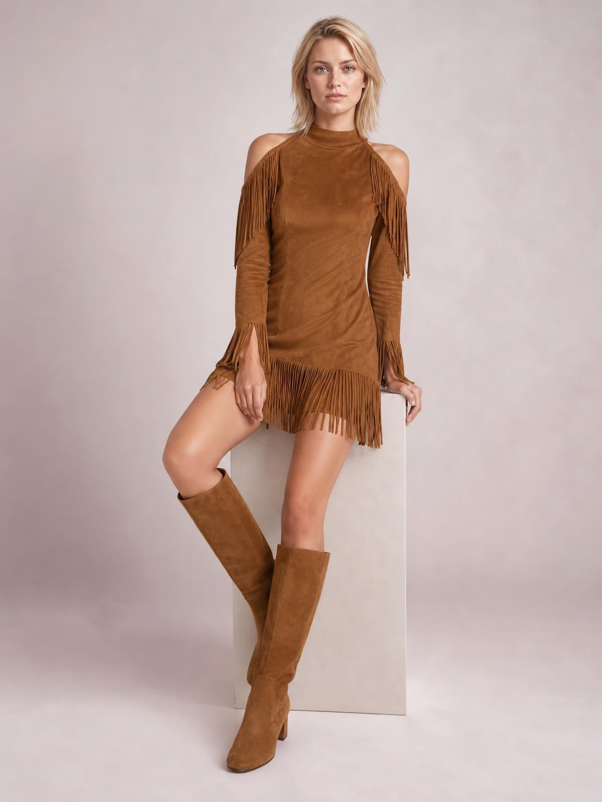 Model poses in a fitted brown cold shoulder mini dress with long fringe on the sleeves and hem, high neckline, and a straight silhouette.