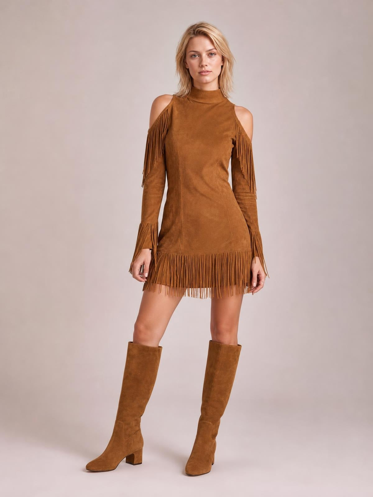 Model stands in a brown cold-shoulder mini dress with a high neckline, long sleeves, fitted silhouette, and dramatic fringe at the shoulders, cuffs, and hem.