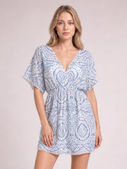 A model stands in a light blue and white boho print beach cover up dress with a surplice neckline, loose kimono sleeves, gathered waist, and relaxed short silhouette.