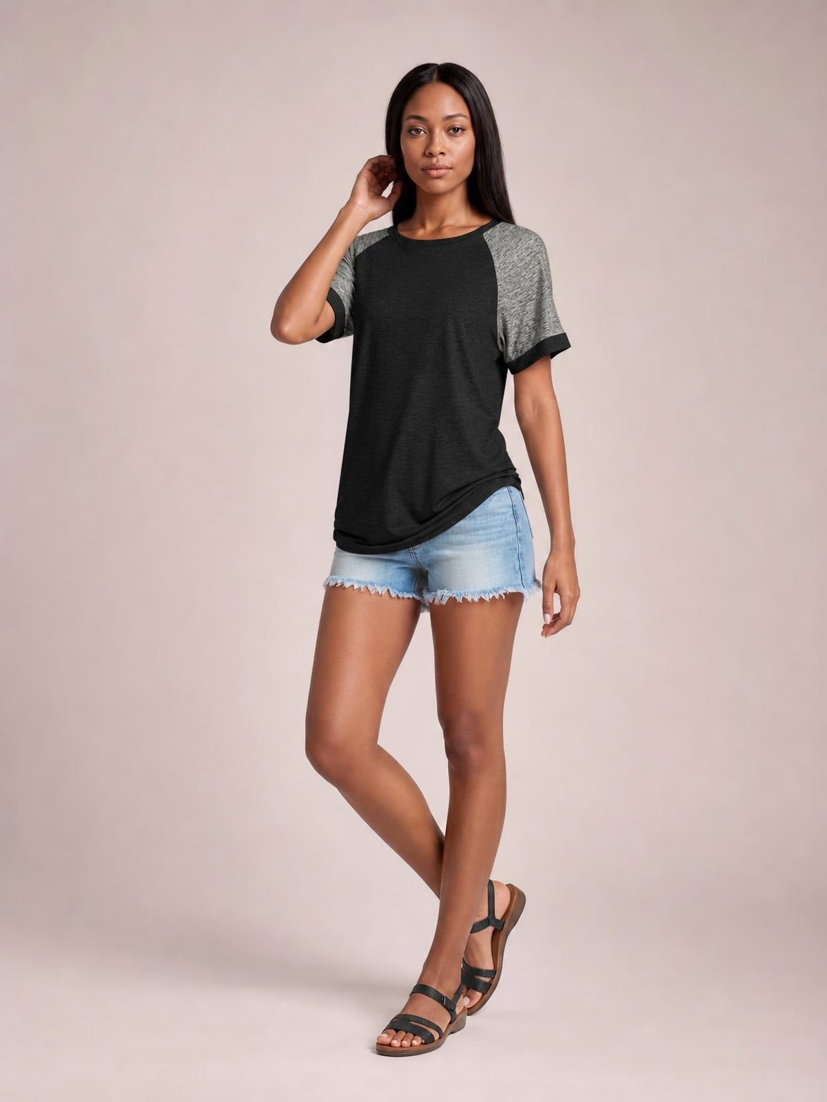 Model poses in a black contrast round neck short sleeve T-shirt with gray raglan sleeves, black trim, and a relaxed straight silhouette.