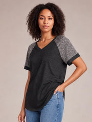 Model poses in a black contrast short-sleeve T-shirt with gray textured sleeves, a round neckline, black sleeve bands, and a relaxed silhouette.