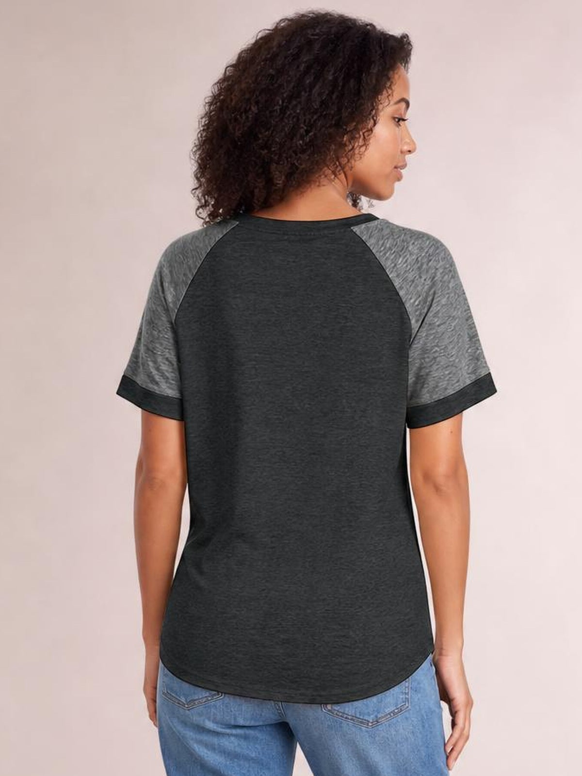 Model shown from the back wearing a charcoal contrast short-sleeve T-shirt with gray raglan sleeves, round neck, cuffed hems, and a curved relaxed silhouette.