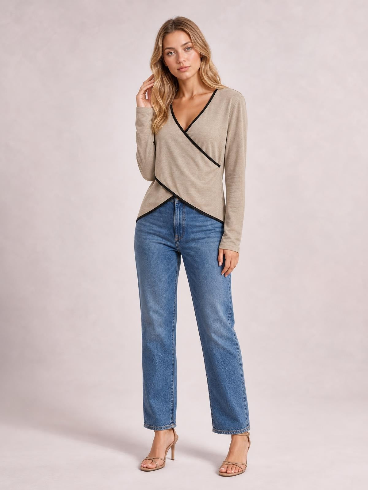 Model poses in a beige long-sleeve T-shirt with black contrast trim, crisscross wrap-style front, V-neckline, and asymmetrical hem.