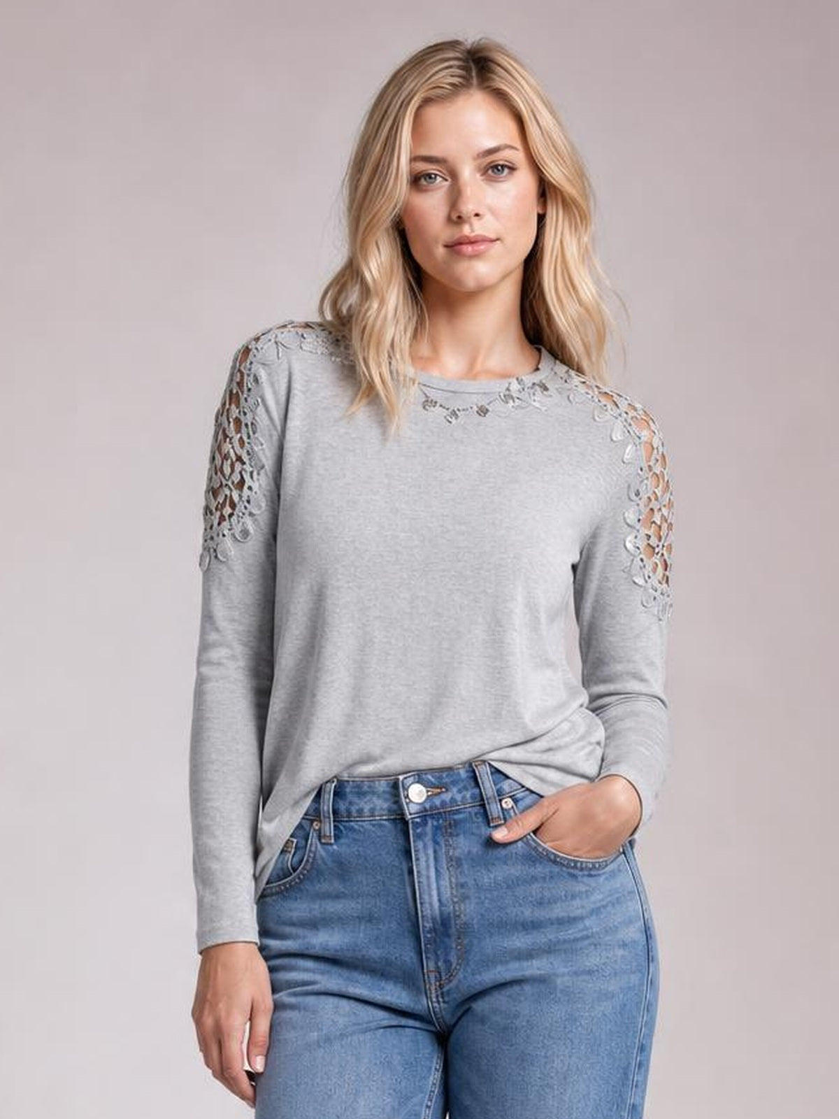 Front-facing model wears a gray round-neck long-sleeve T-shirt with lace cutout detailing across the shoulders and sleeves in a relaxed silhouette.