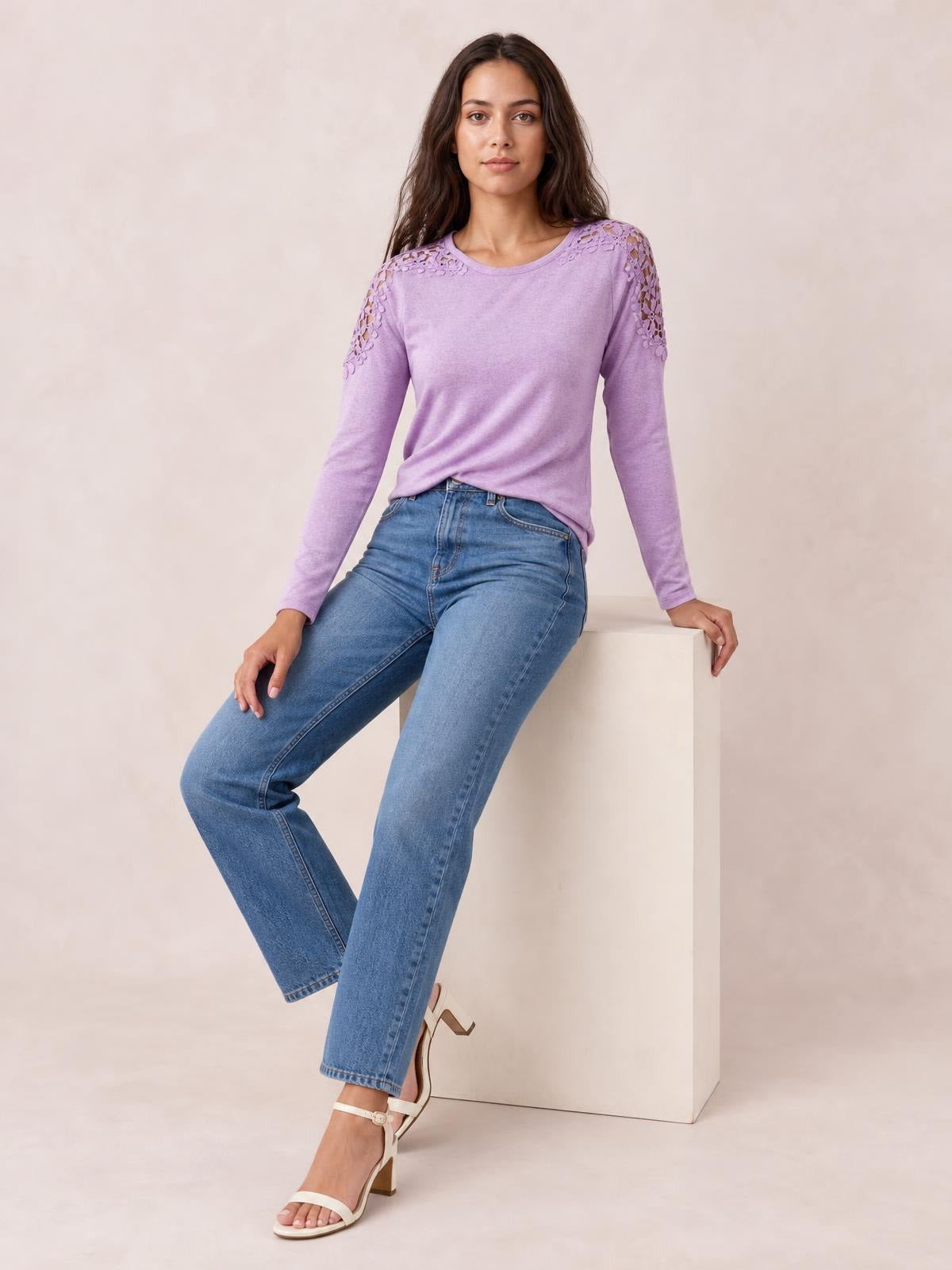 Model seated in a lavender cutout round neck long sleeve T-shirt with lace detailing at the shoulders and a relaxed silhouette.