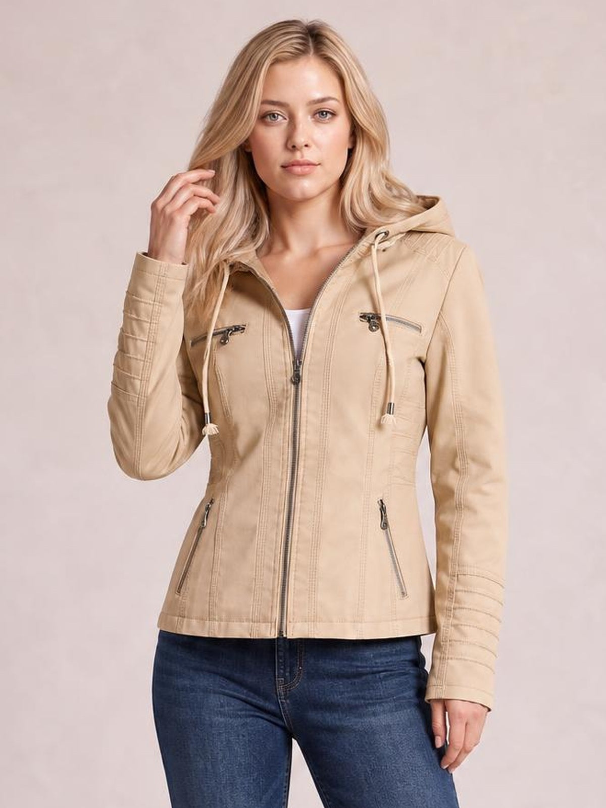 A model poses in a beige faux leather moto jacket with a hood, drawstrings, zip closure, seam detailing, zippered pockets, and a regular fit.