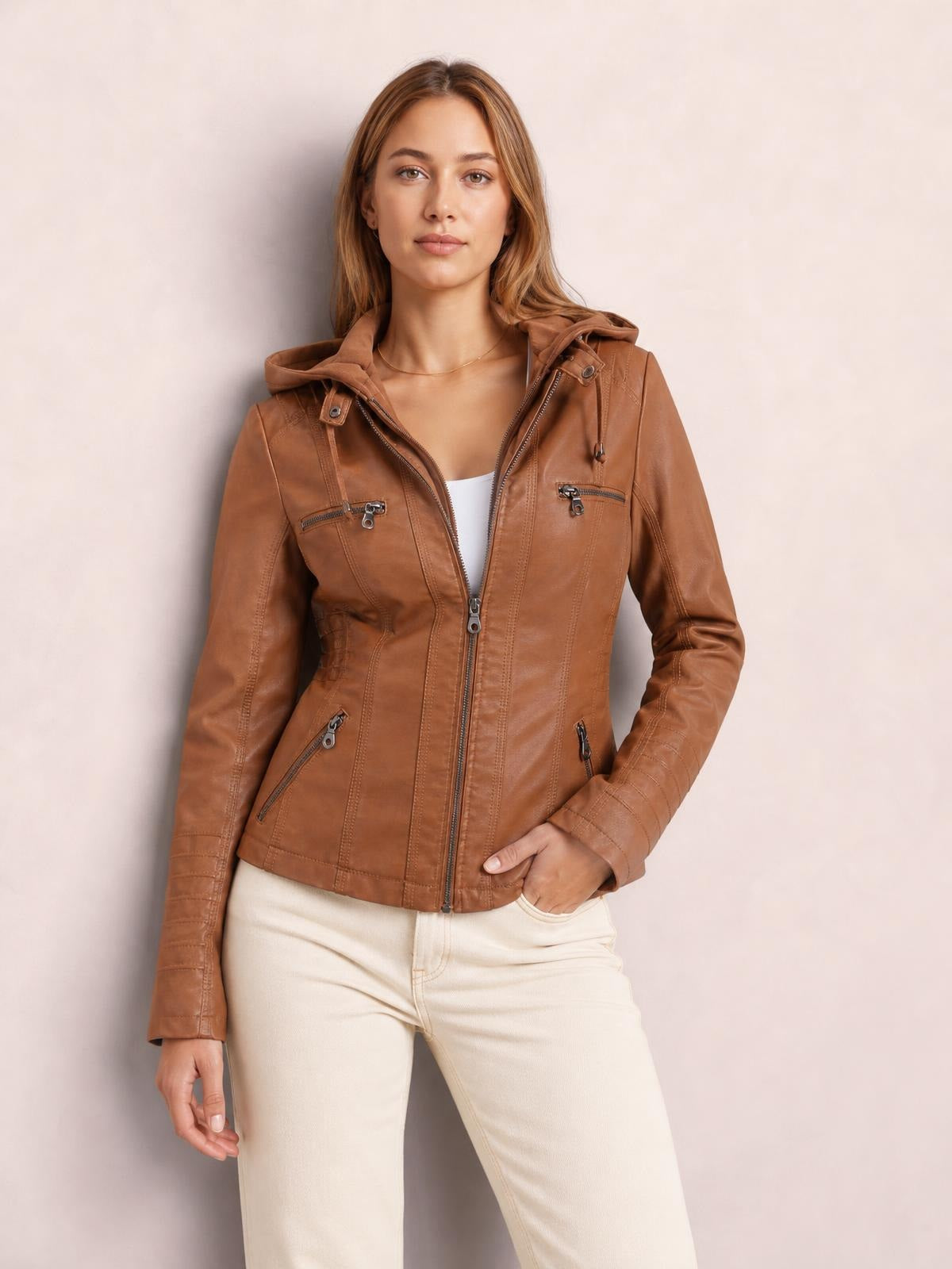 Model wears a brown faux leather moto jacket with a hood, zip closure, seam detailing, and multiple zippered pockets in a regular silhouette.