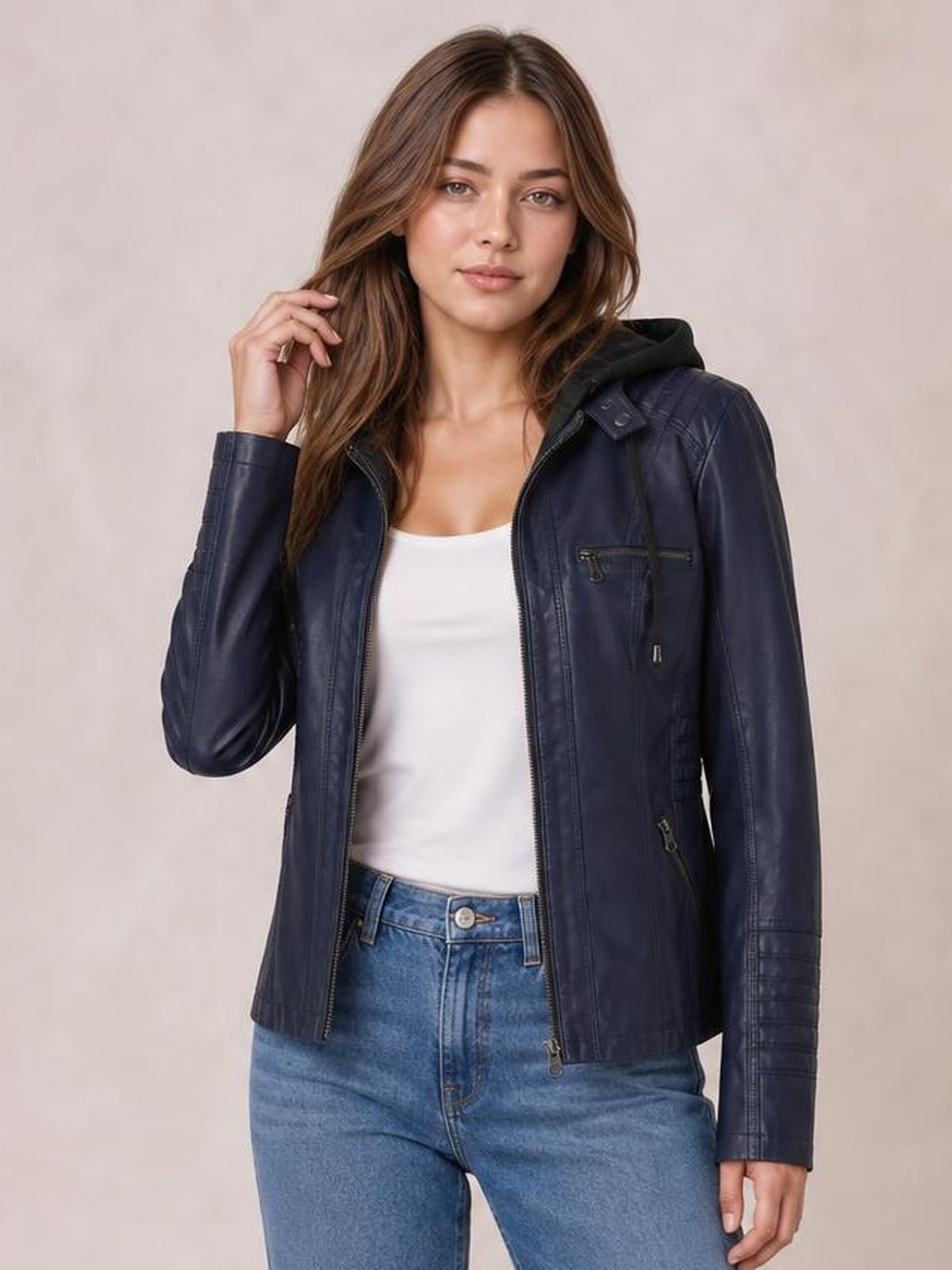 Model poses in a navy faux leather moto jacket with a hood, open front zipper, seam detailing, zippered pockets, and a regular silhouette.